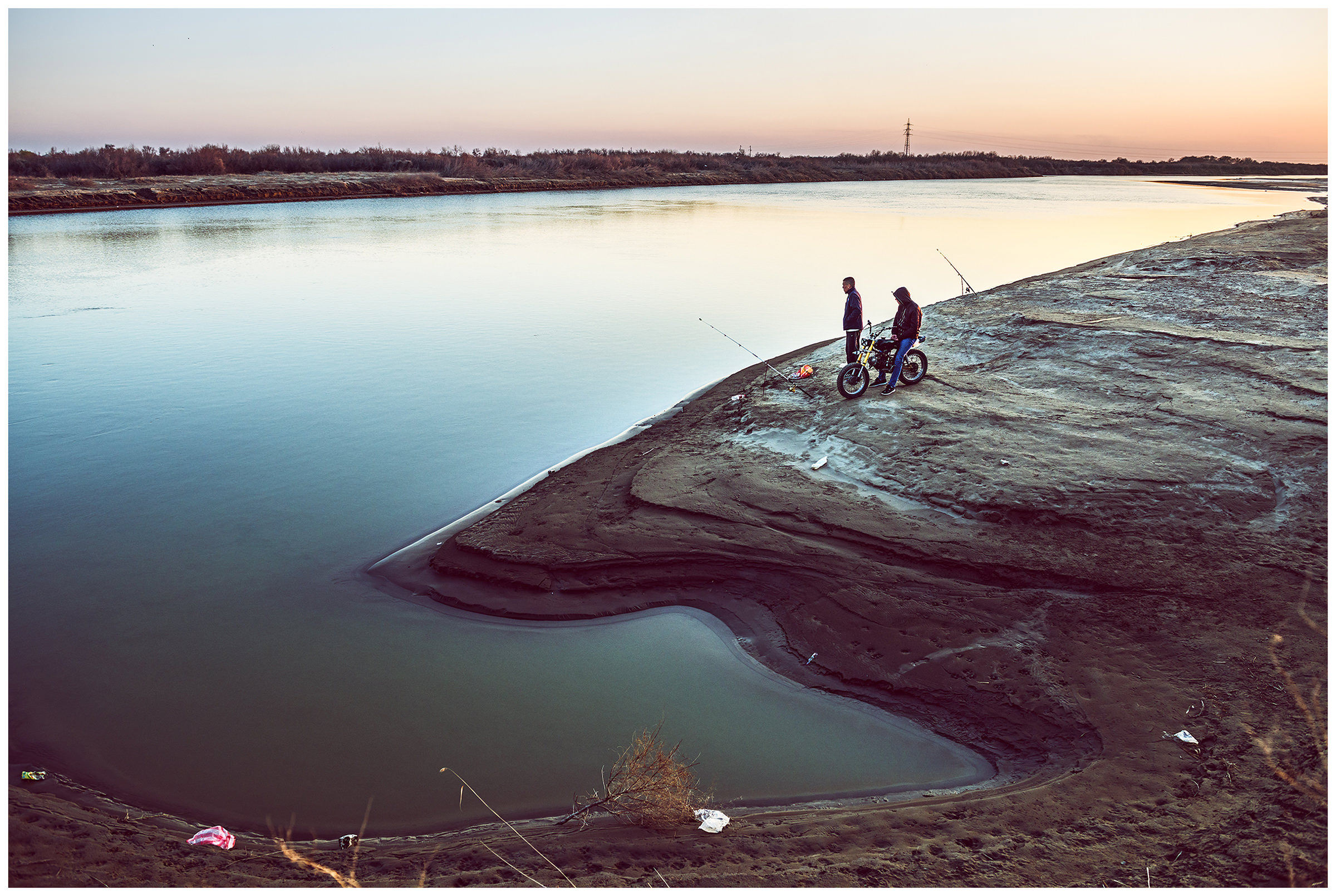 Two men stand on the right bank of the river Syr Darya