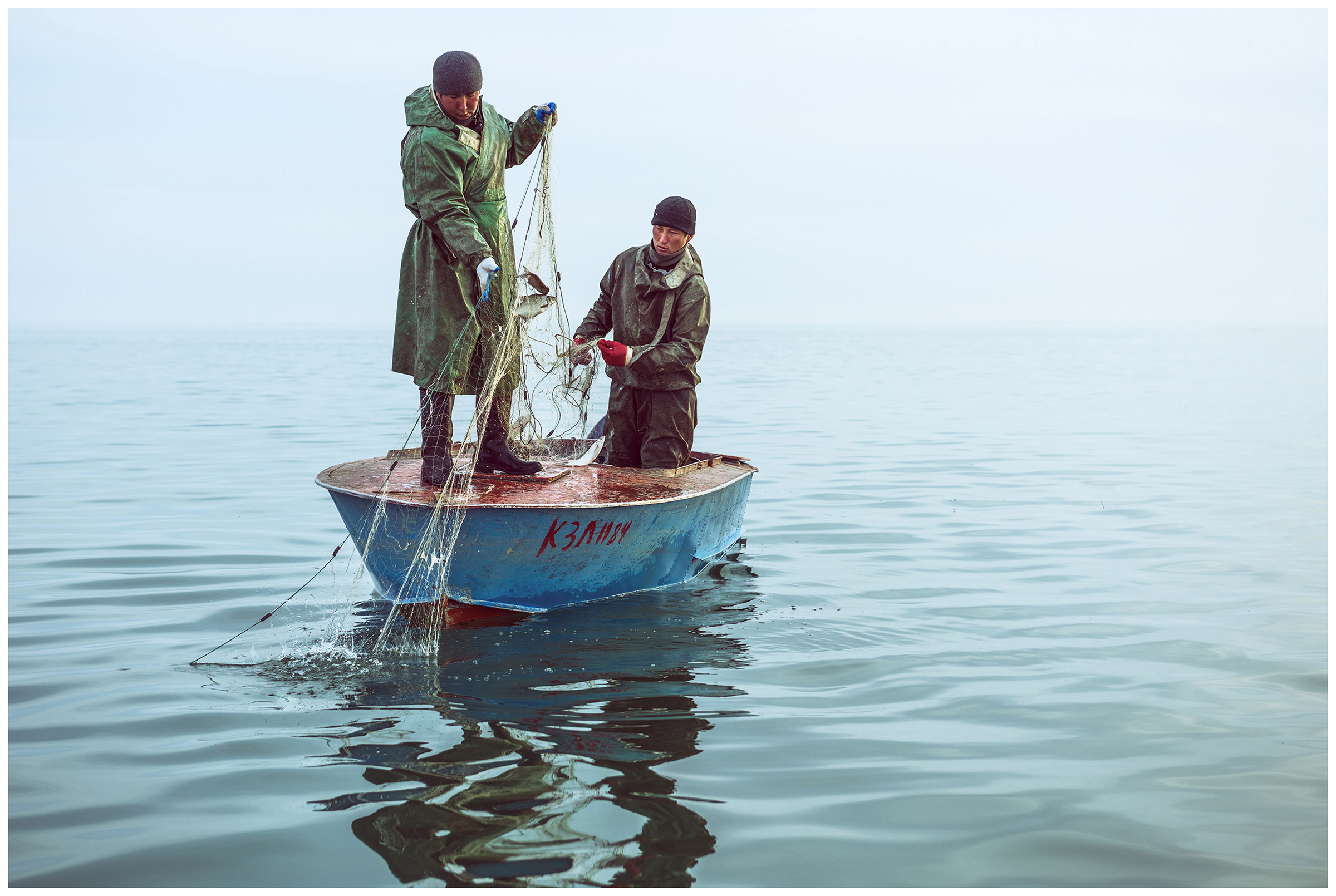 Two fishermen get nets out of the water