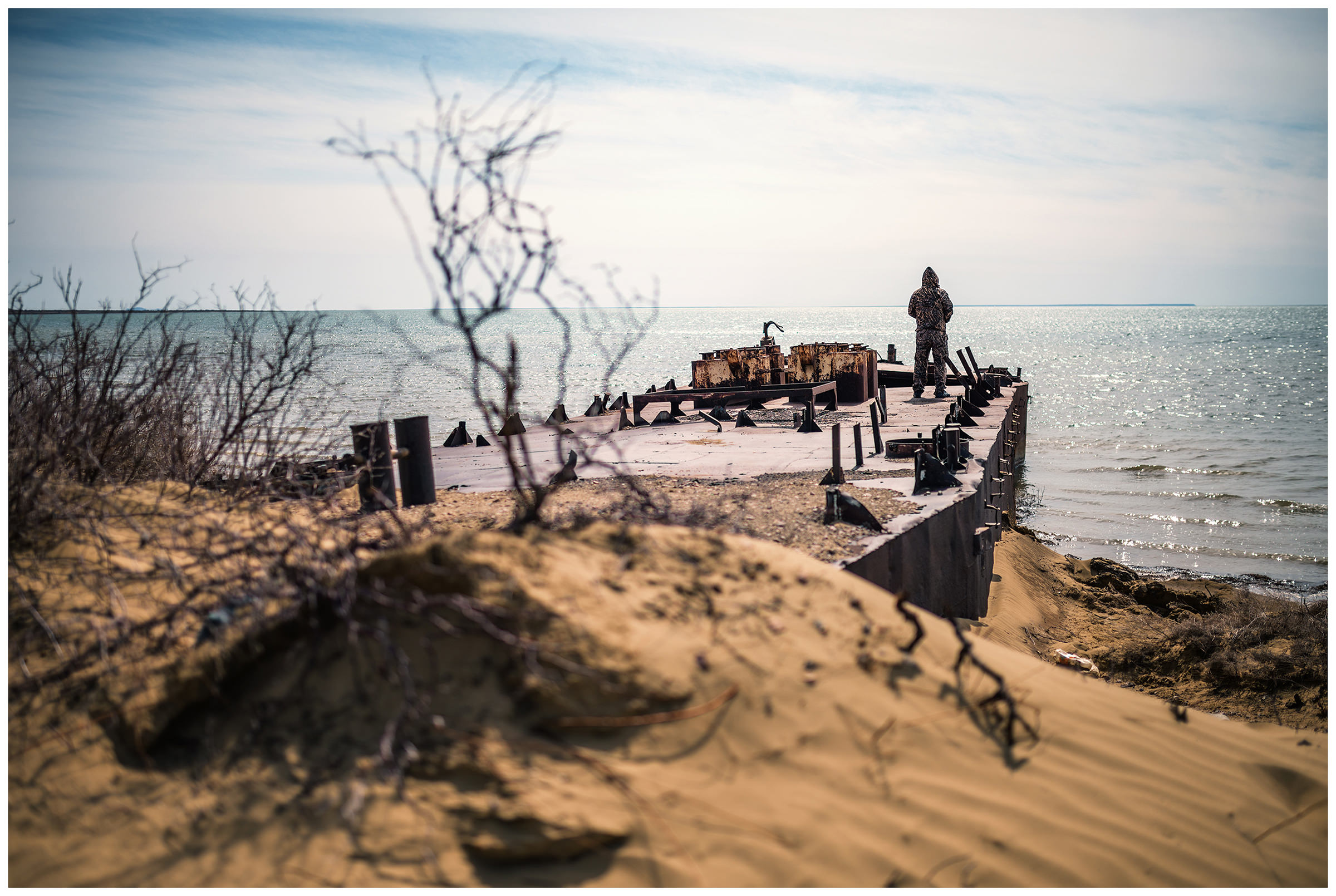 A guide and fisherman is standing on a shipwreck on the coast of the Aral Sea