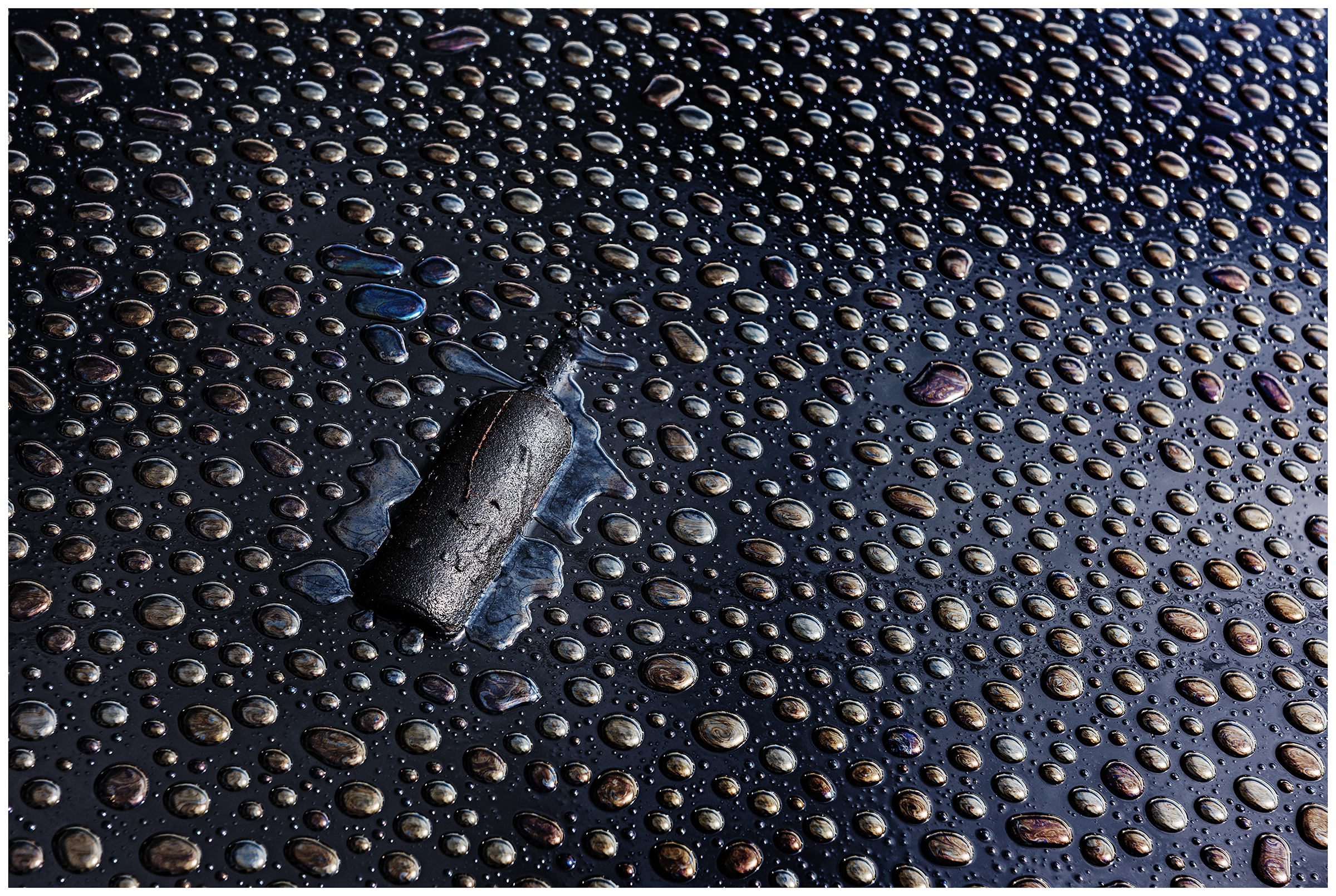A bottle lies in the oil on the site of the former ship repair yard with the raindrops on the surface