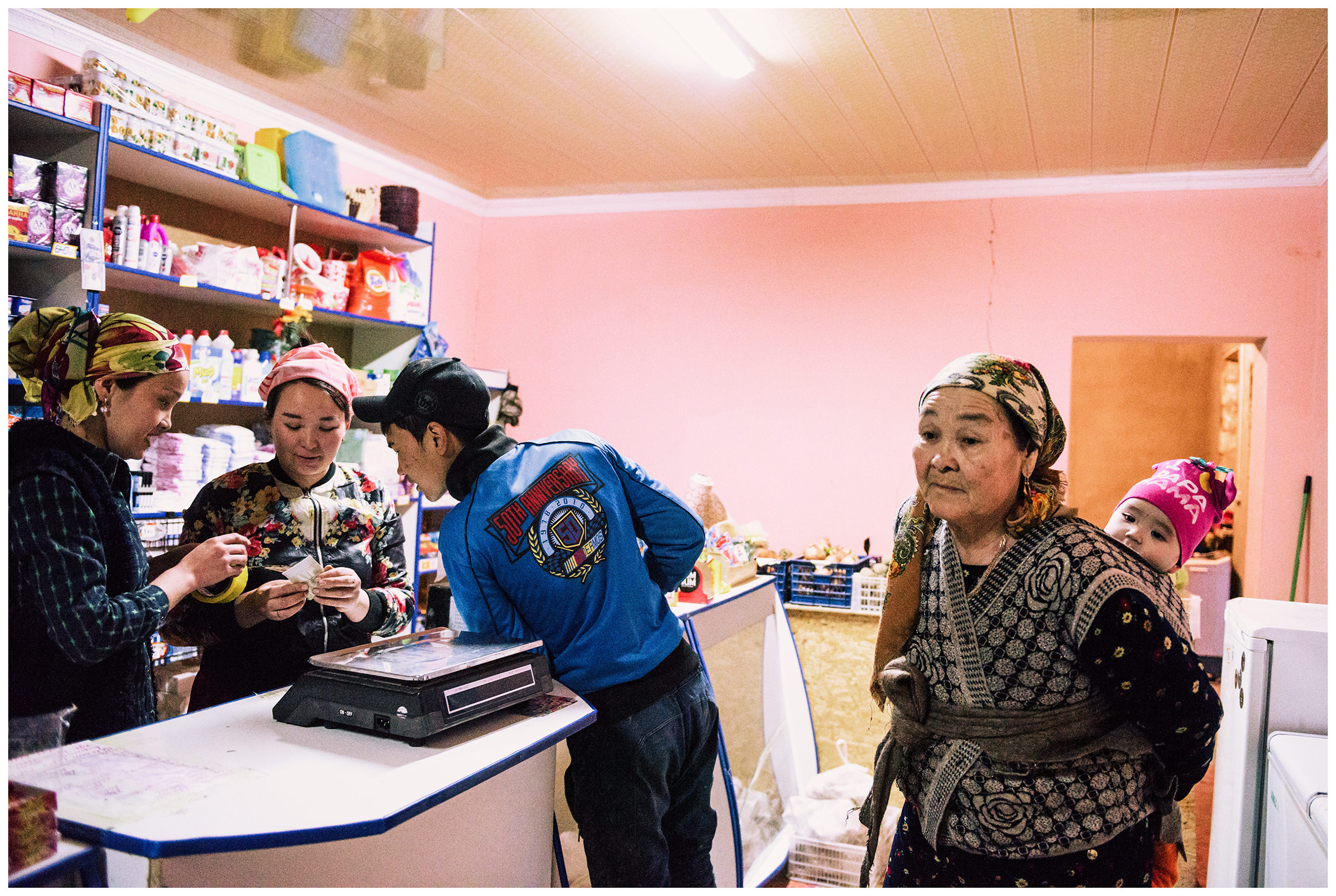 An old woman standing in a village shop in the fishing village Bogen with a baby in a sling