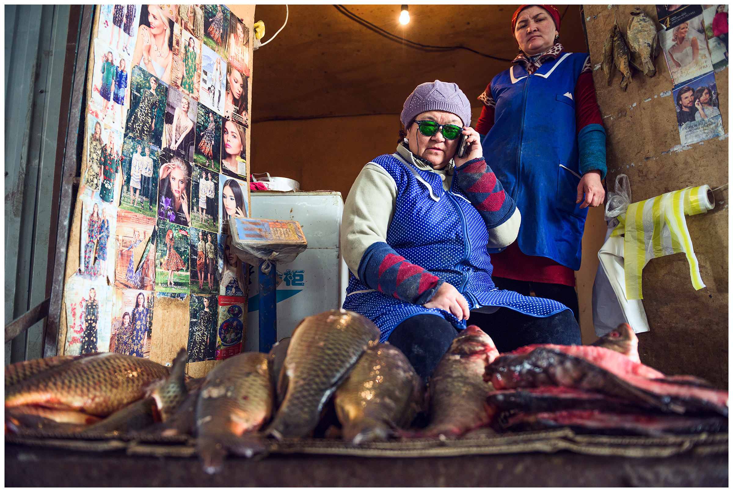 A fish seller calls her fish stand at the market in the town of Aral