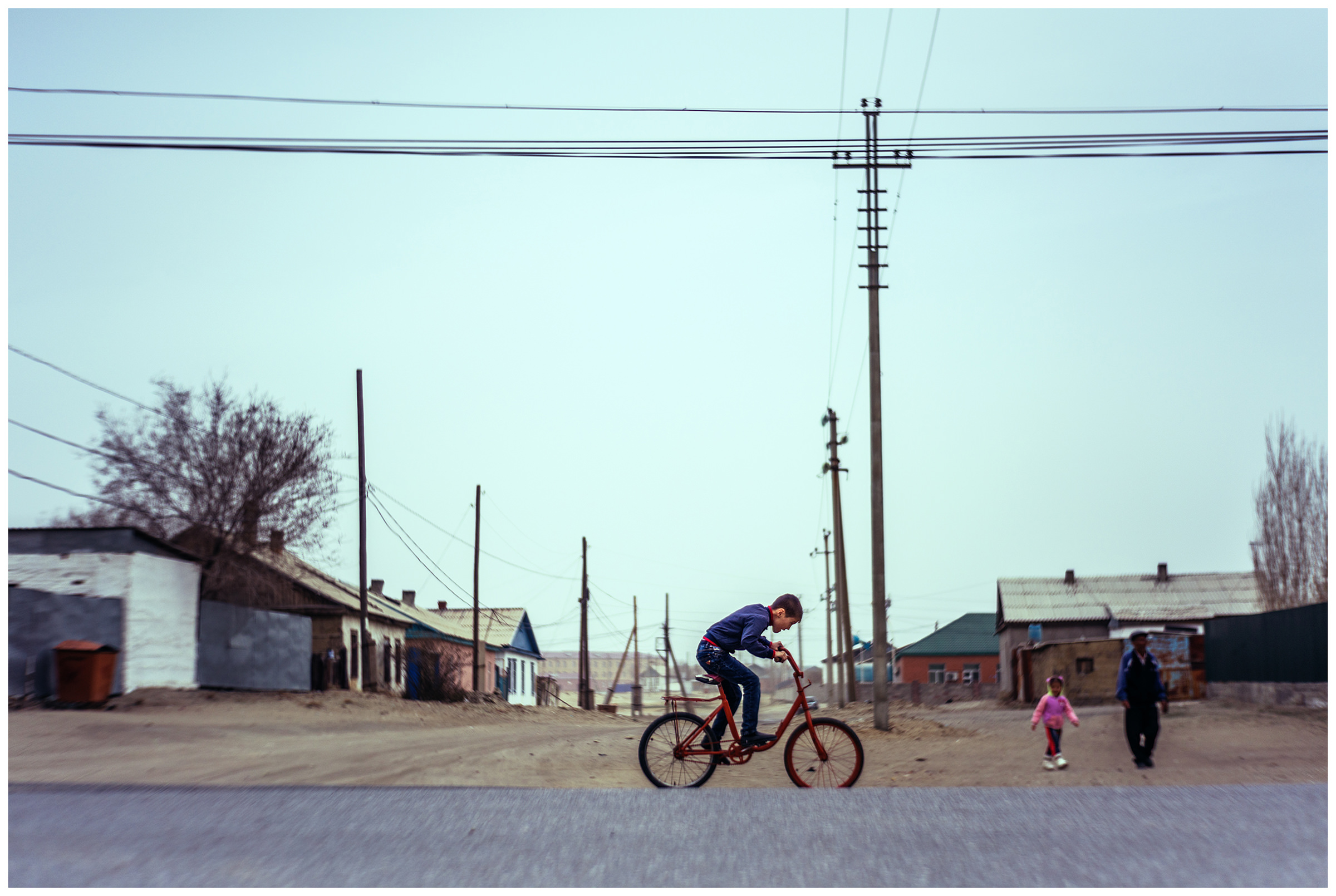 A boy is riding a bicycle on a road from Aral