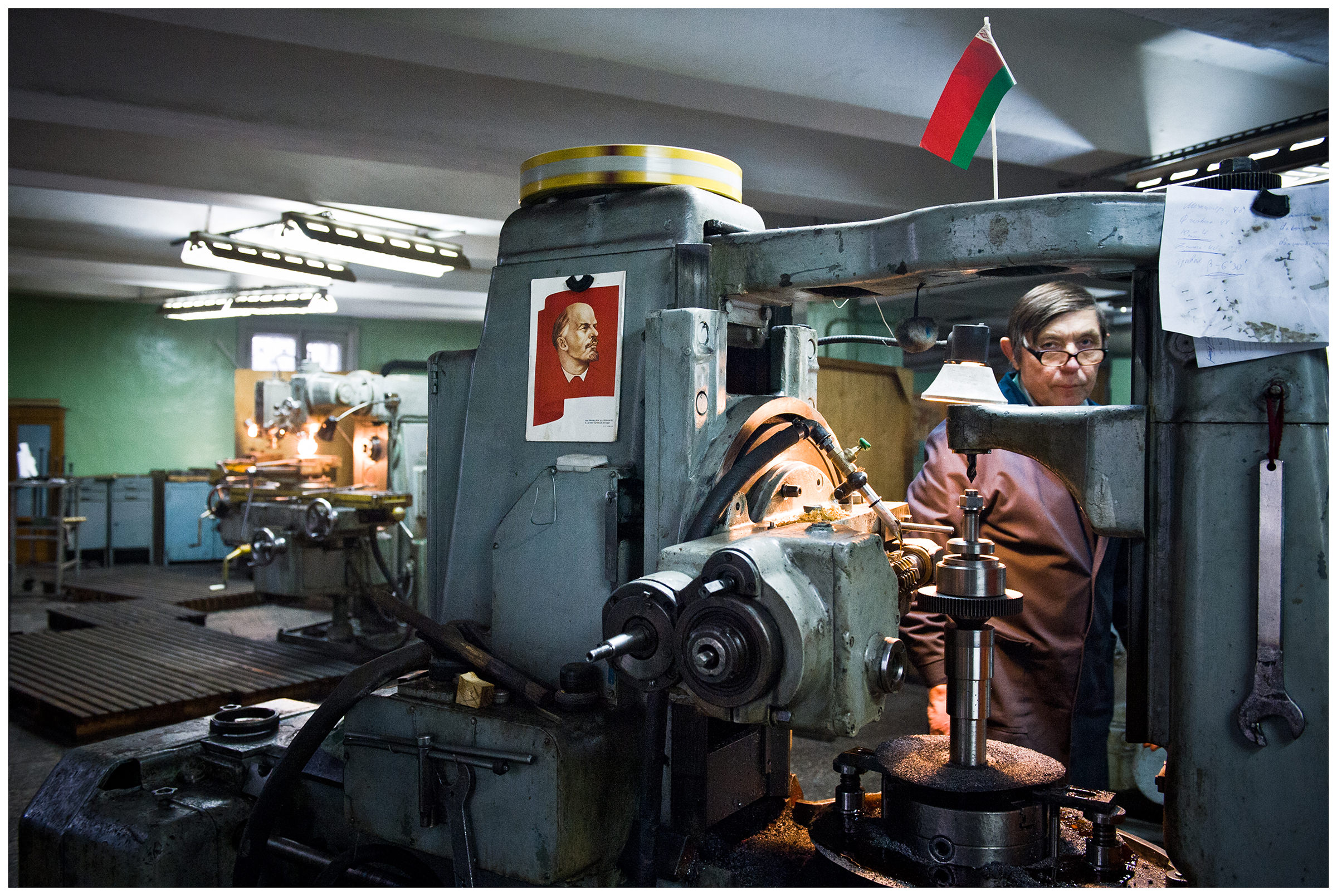 Minsk, Belarus, the publishing house "Pechatny Combinat". A worker walks past a machine tool with Soviet and Belarusian symbolism.