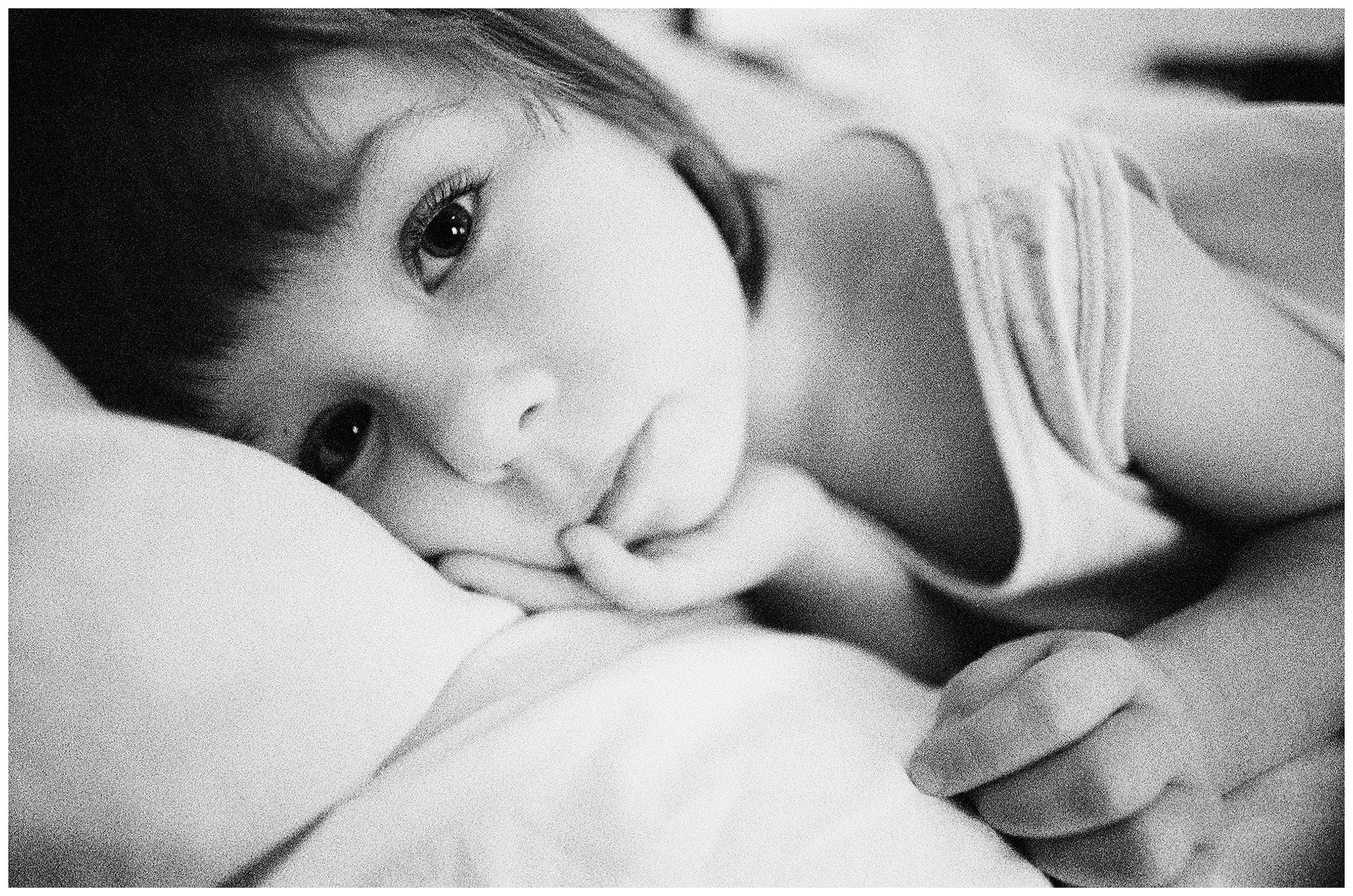 Minsk, Belarus. A psychophysically handicapped girl lies in his bed.