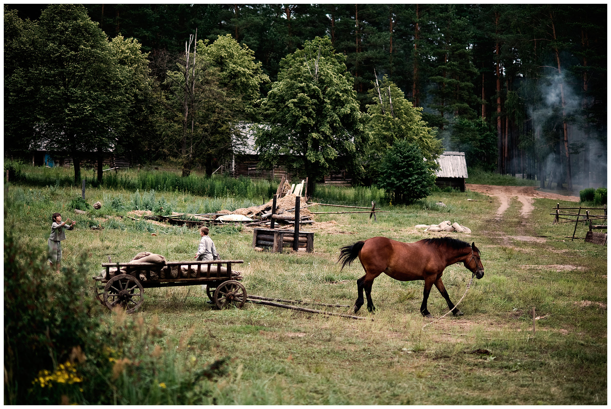 Belarus. Two boys play a homemade ball in a village. In the foreground a horse is grazing.