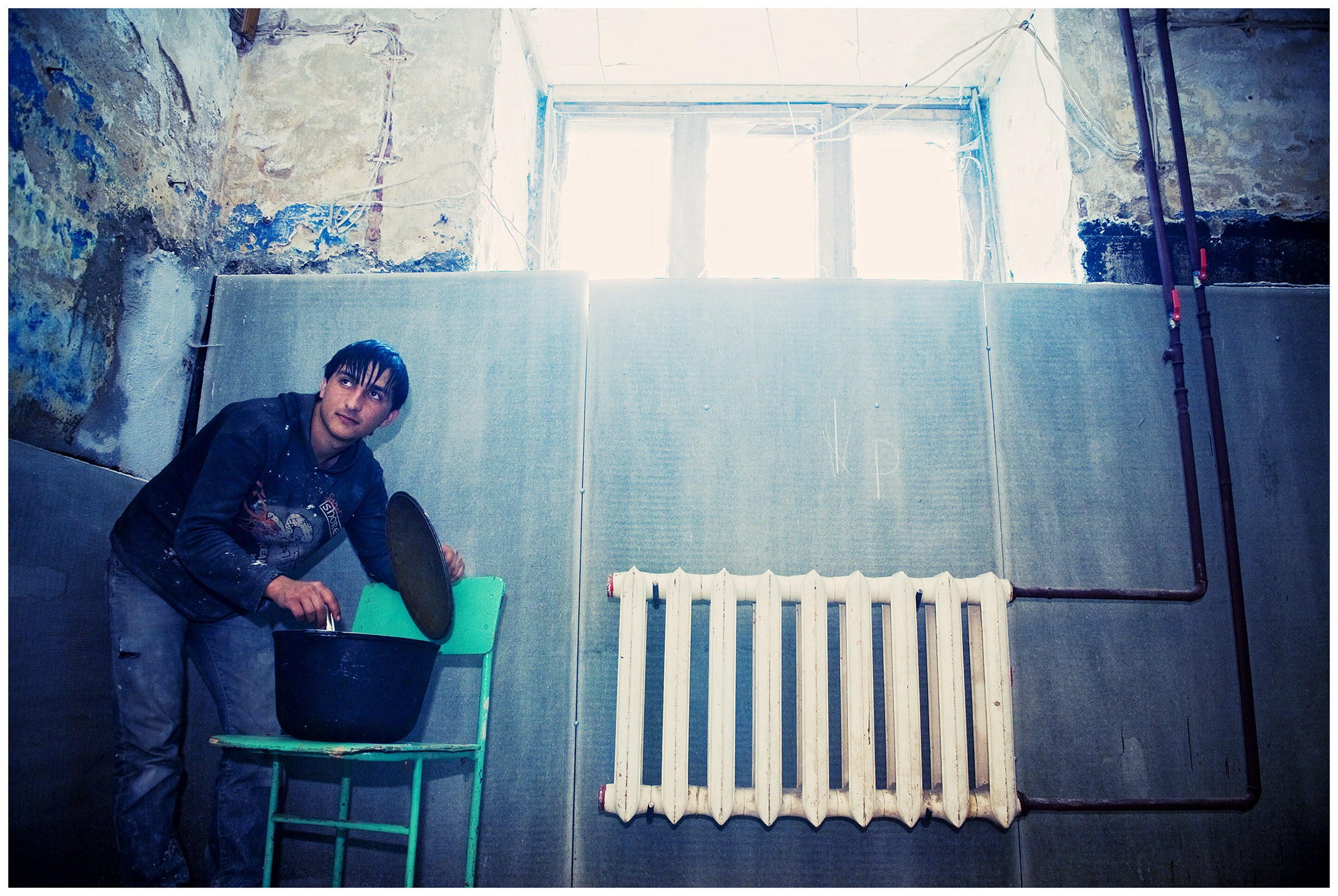 Vyborg, Russia. A Georgian guest worker prepares food in a cellar which he and his colleagues use as an apartment.