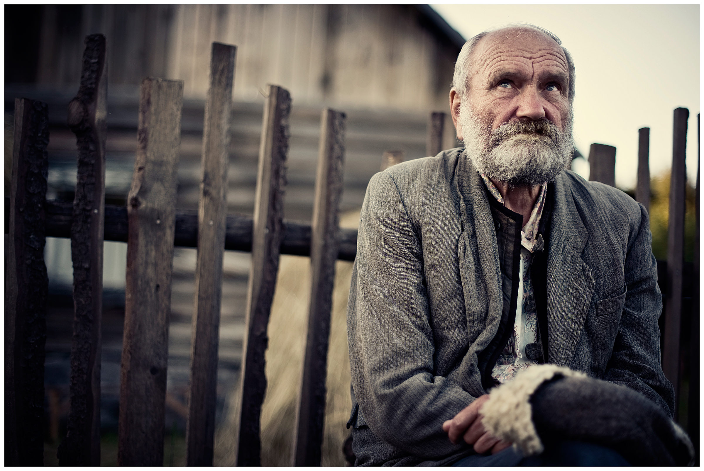 Belarus, village of Chereshlya. An old man is sitting on a bench in front of a village house.