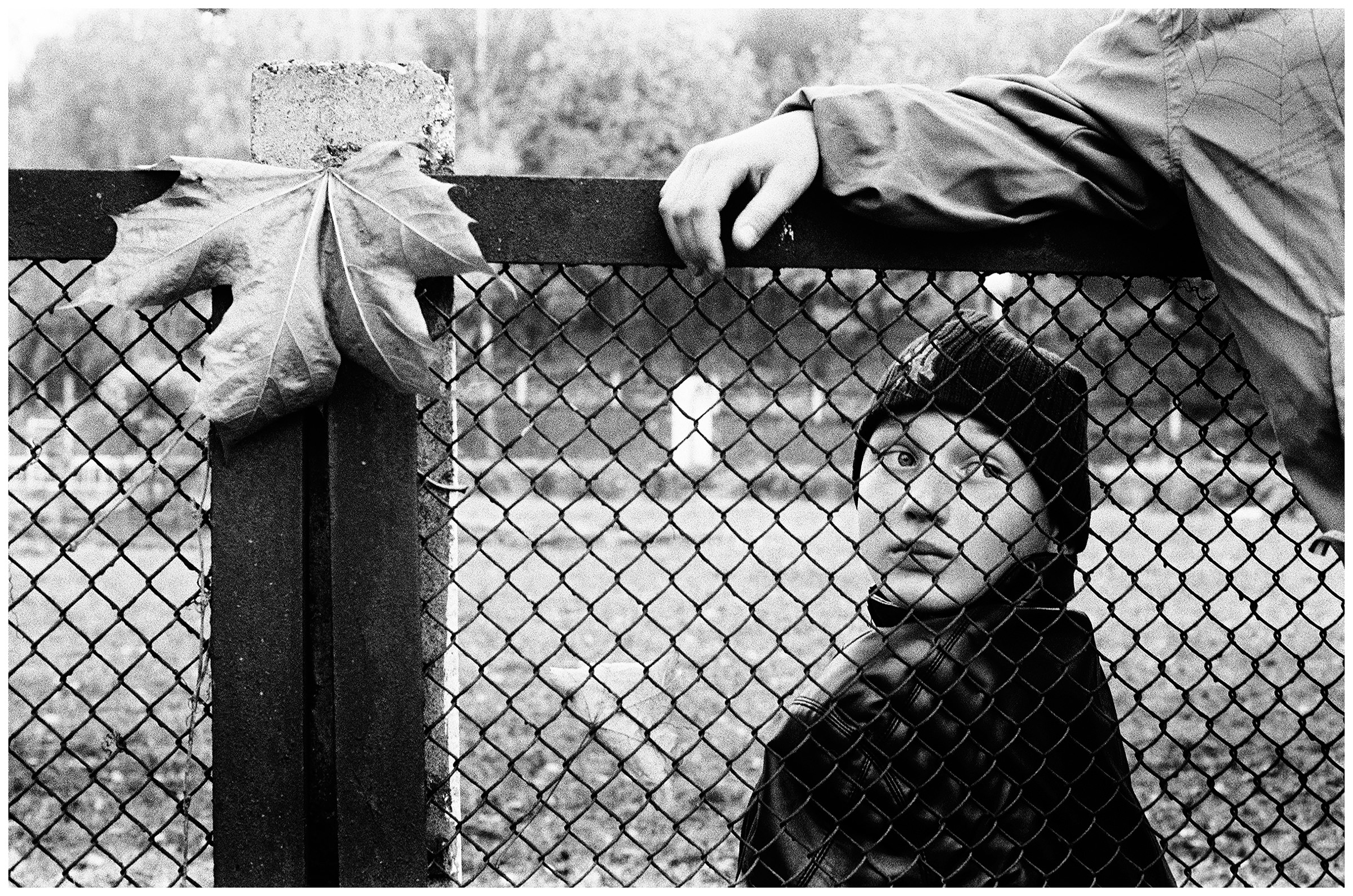 Minsk, Belarus. A boy looks through a fence while gardening in a children's home.