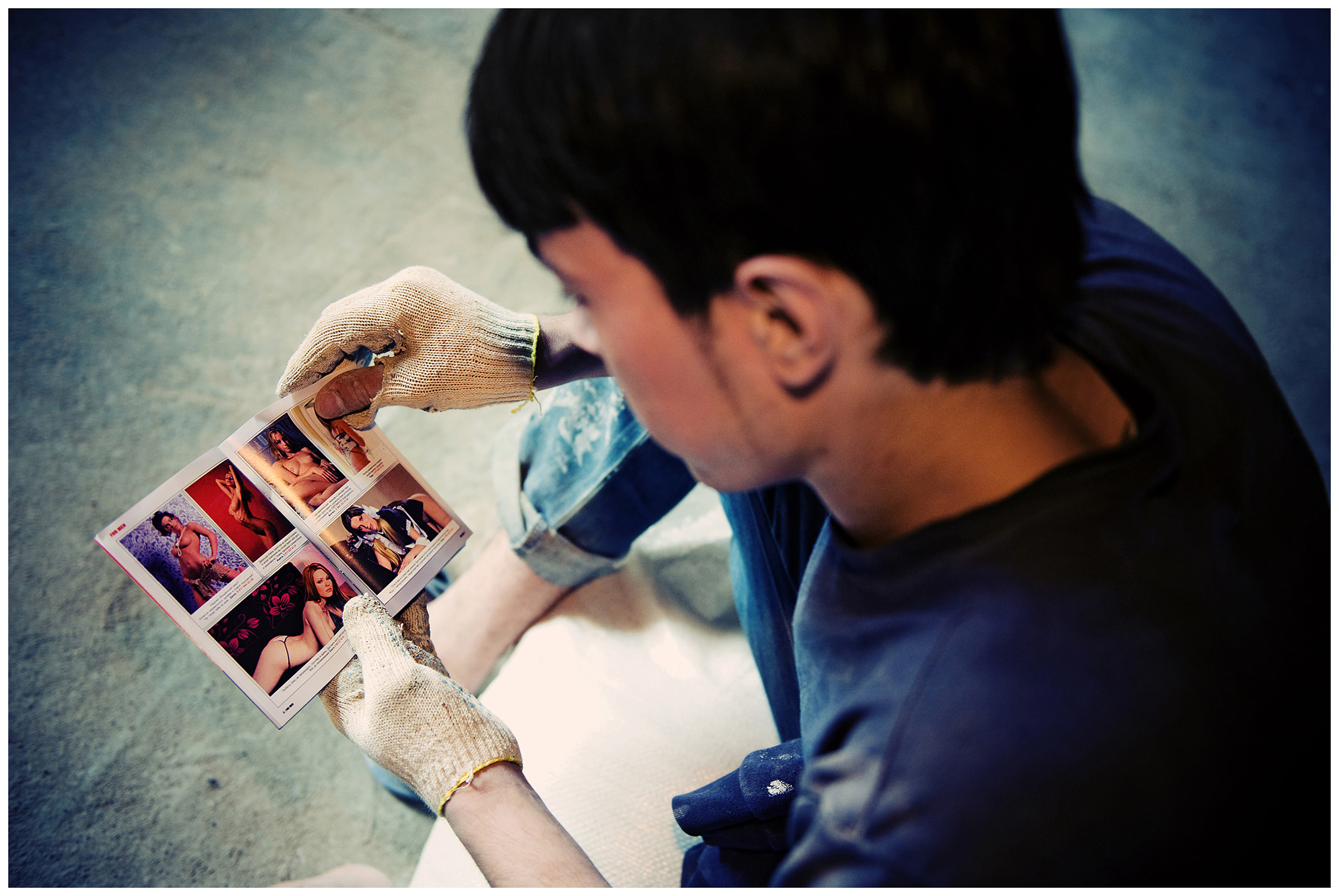 Saint Petersburg, Russia. An Uzbek guest worker leafs through a free catalogue of prostitutes at a construction site.