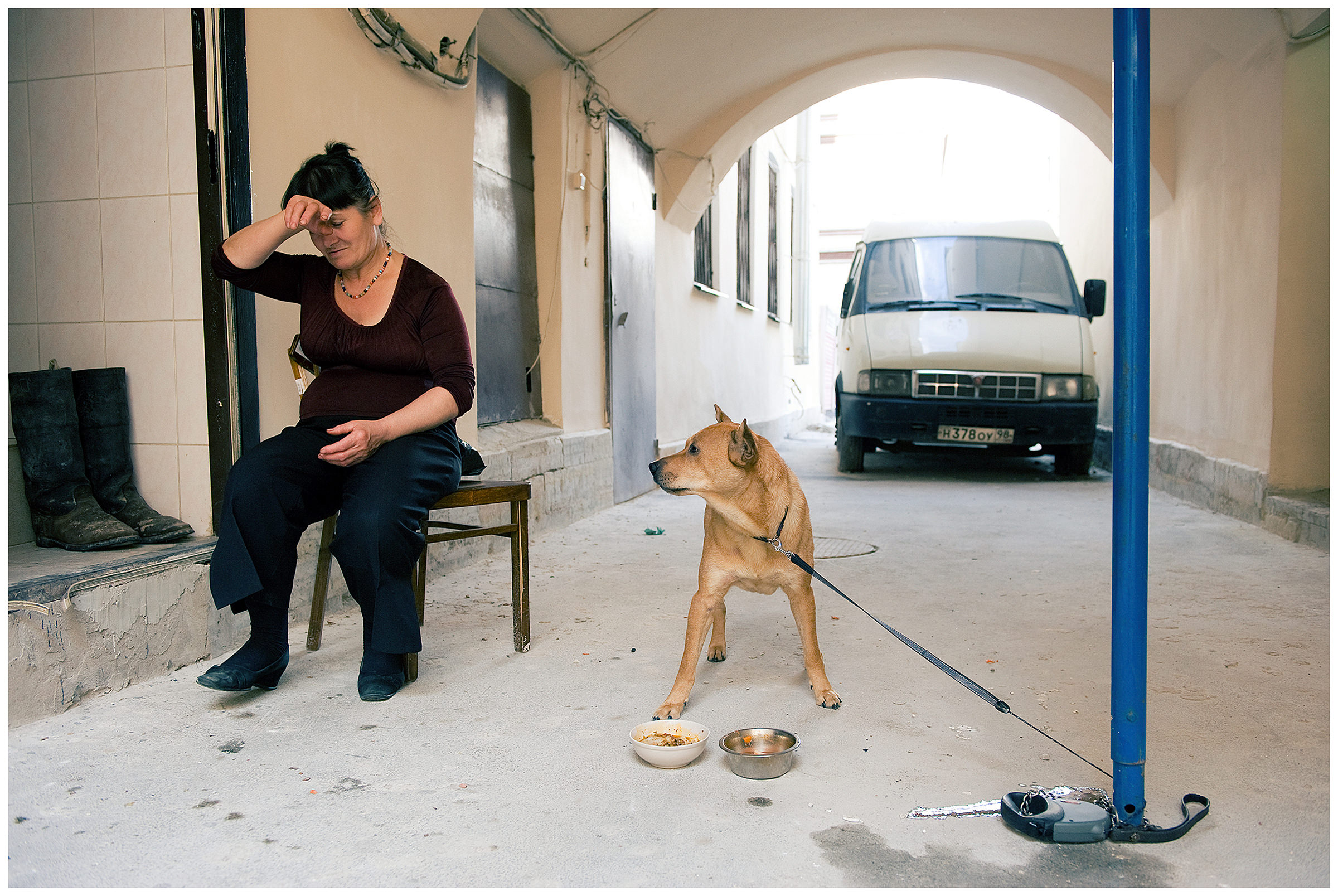 Saint Petersburg, Russia. A Georgian guest worker sits with a dog in the backyard of a Georgian pub.