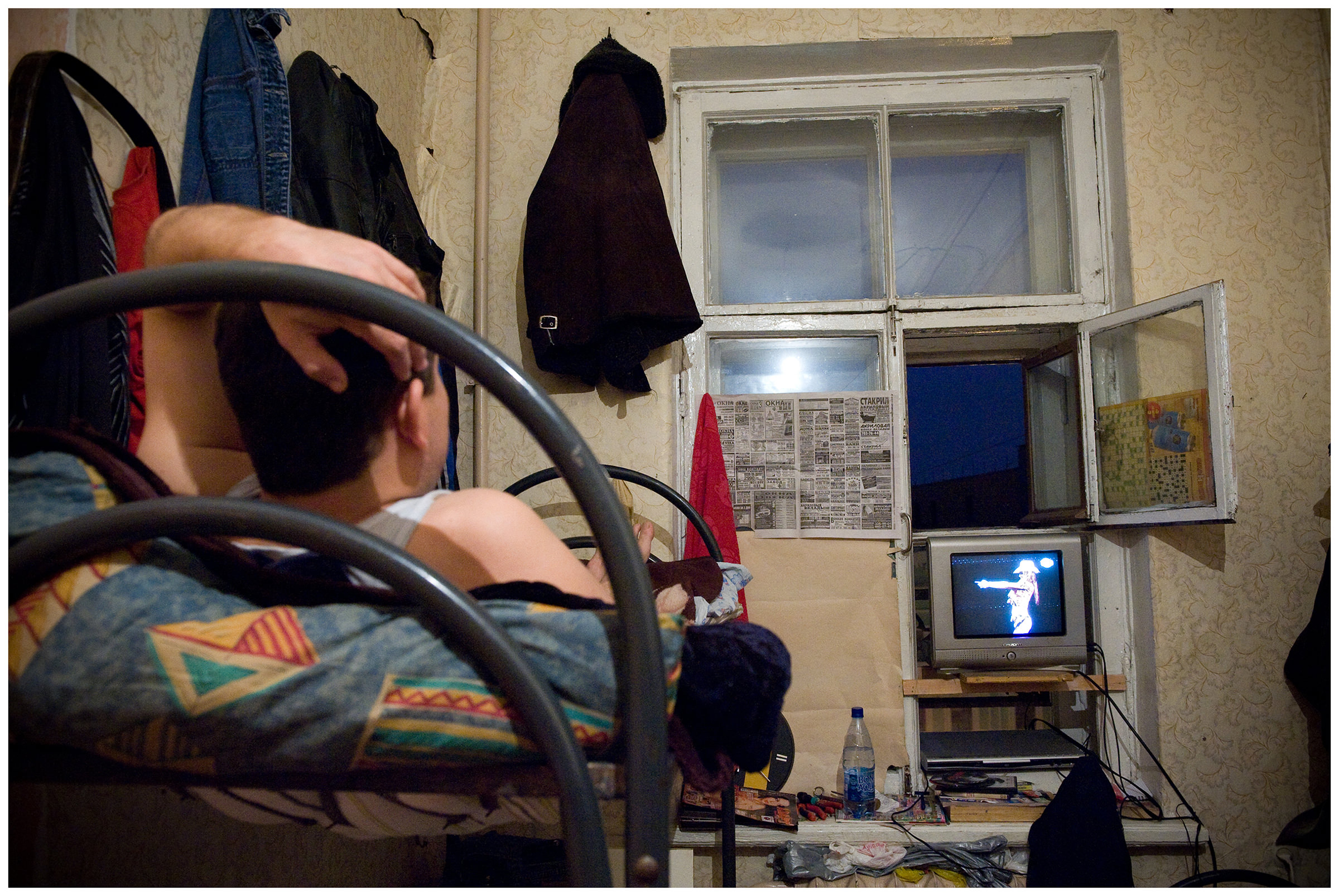 Saint Petersburg, Russia. An Uzbek guest worker watches television in his rented apartment.