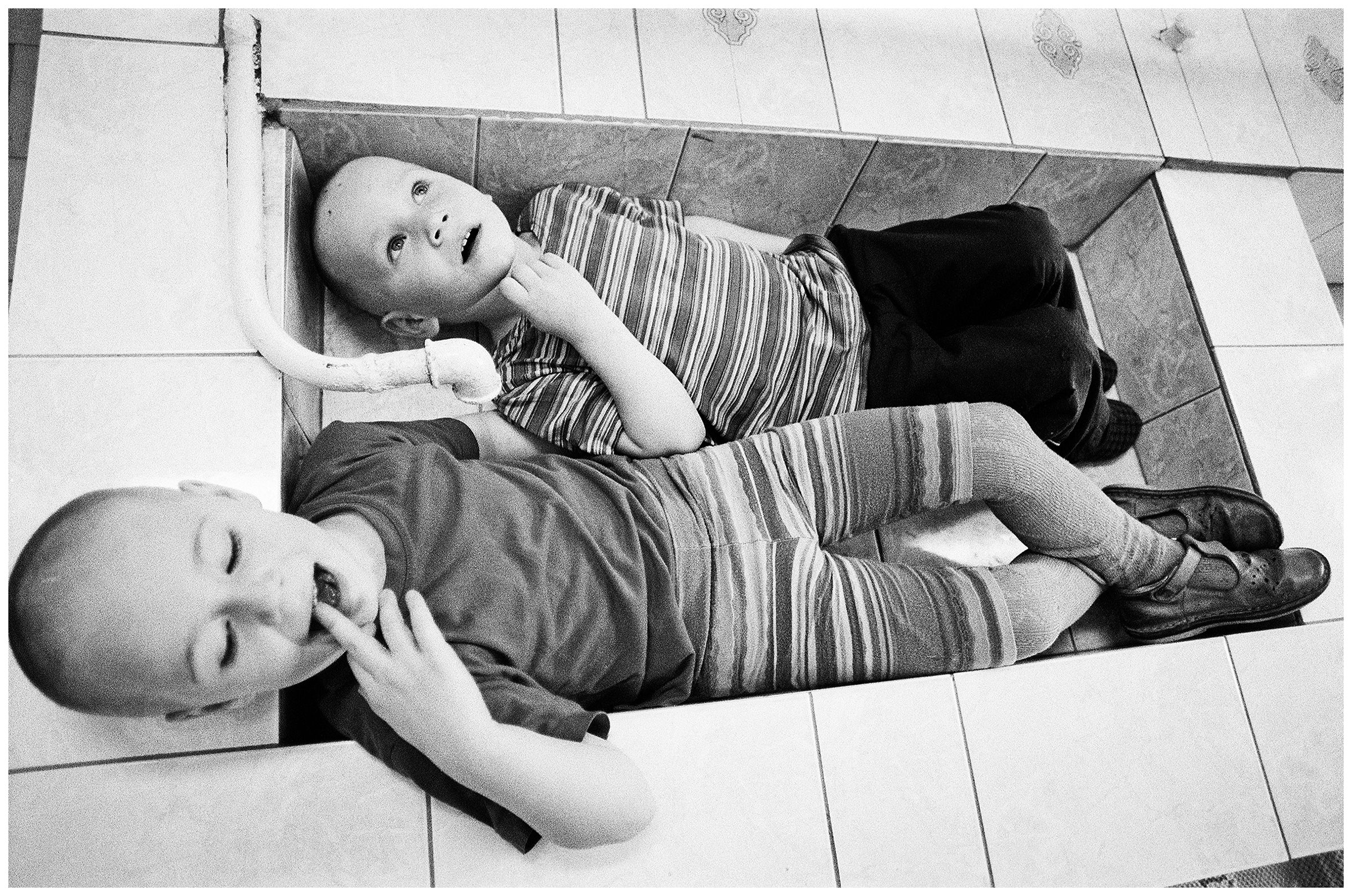 Minsk, Belarus. Two children lie in a washbasin in the swimming pool. The swimming pool has no water because the water in this district does not meet medical standards.