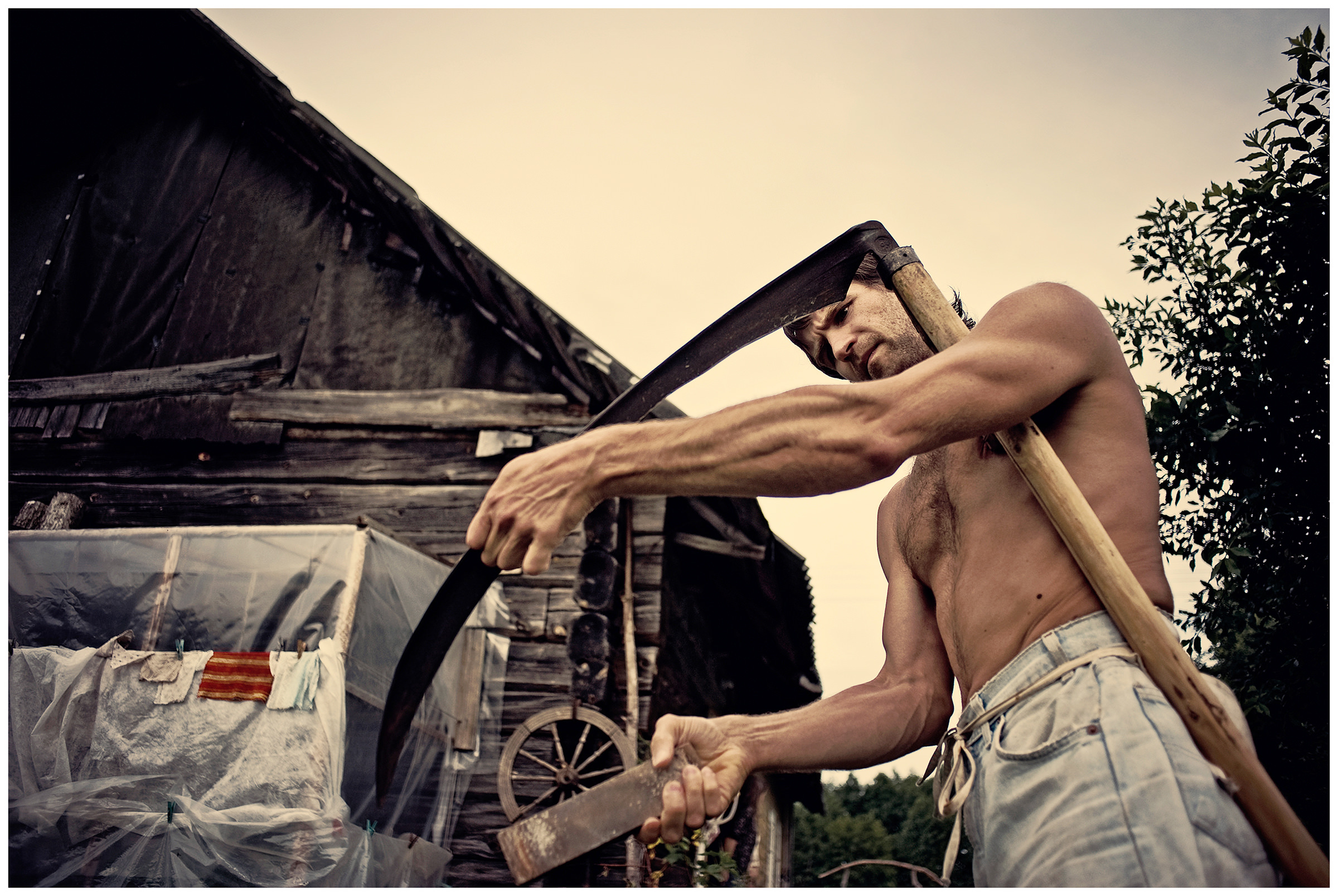 Belarus, village of Chereshlya. A man sharpens a scythe.