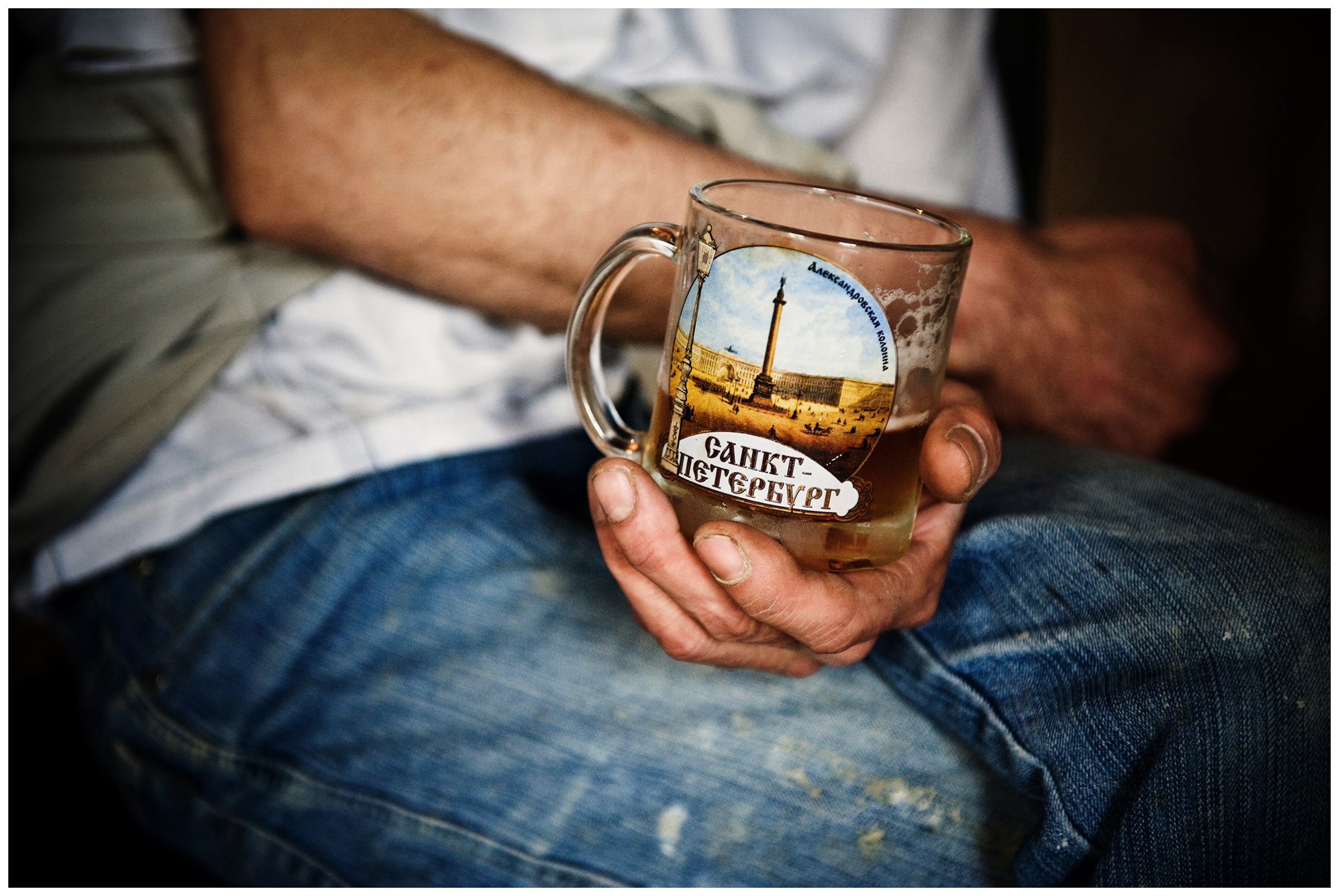 Saint Petersburg, Russia. An Uzbek migrant worker is holding a glass of beer with the words Saint Petersburg in his hand.