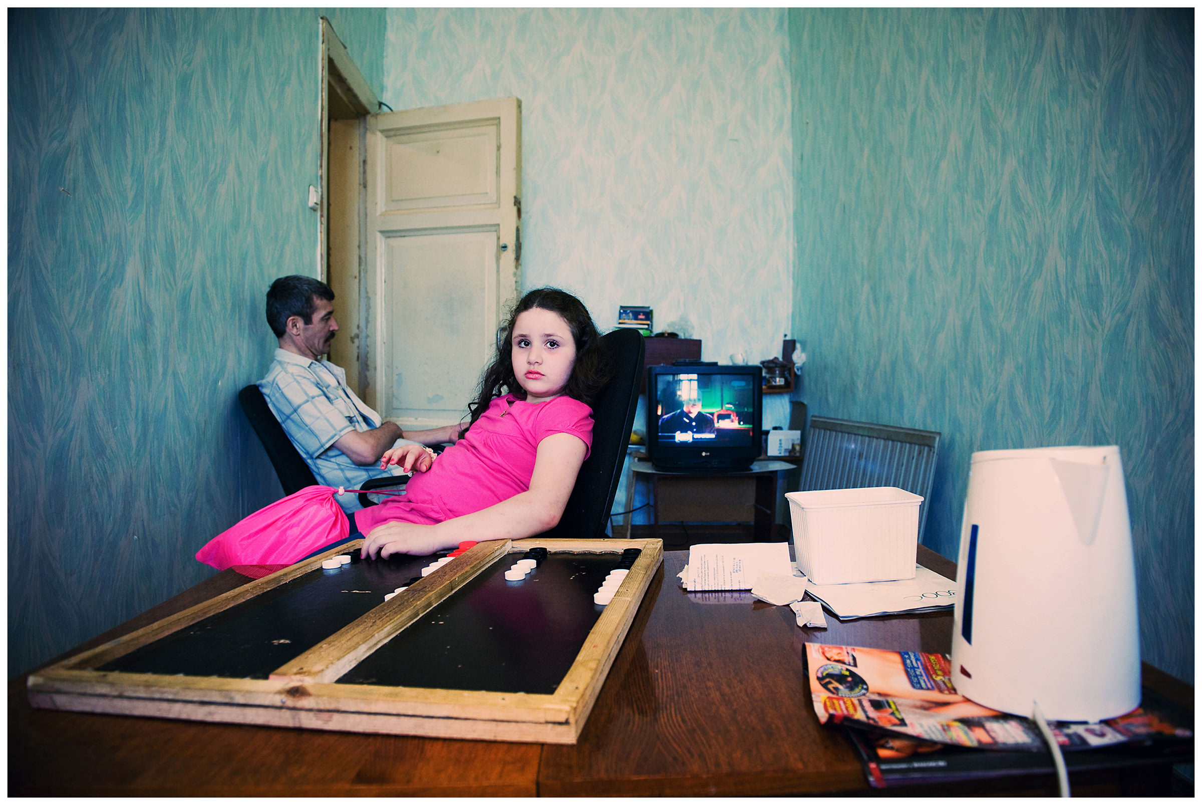 Saint Petersburg, Russia. An Uzbek guest worker and the daughter of his Georgian colleague sit in their rented apartment in front of the TV.