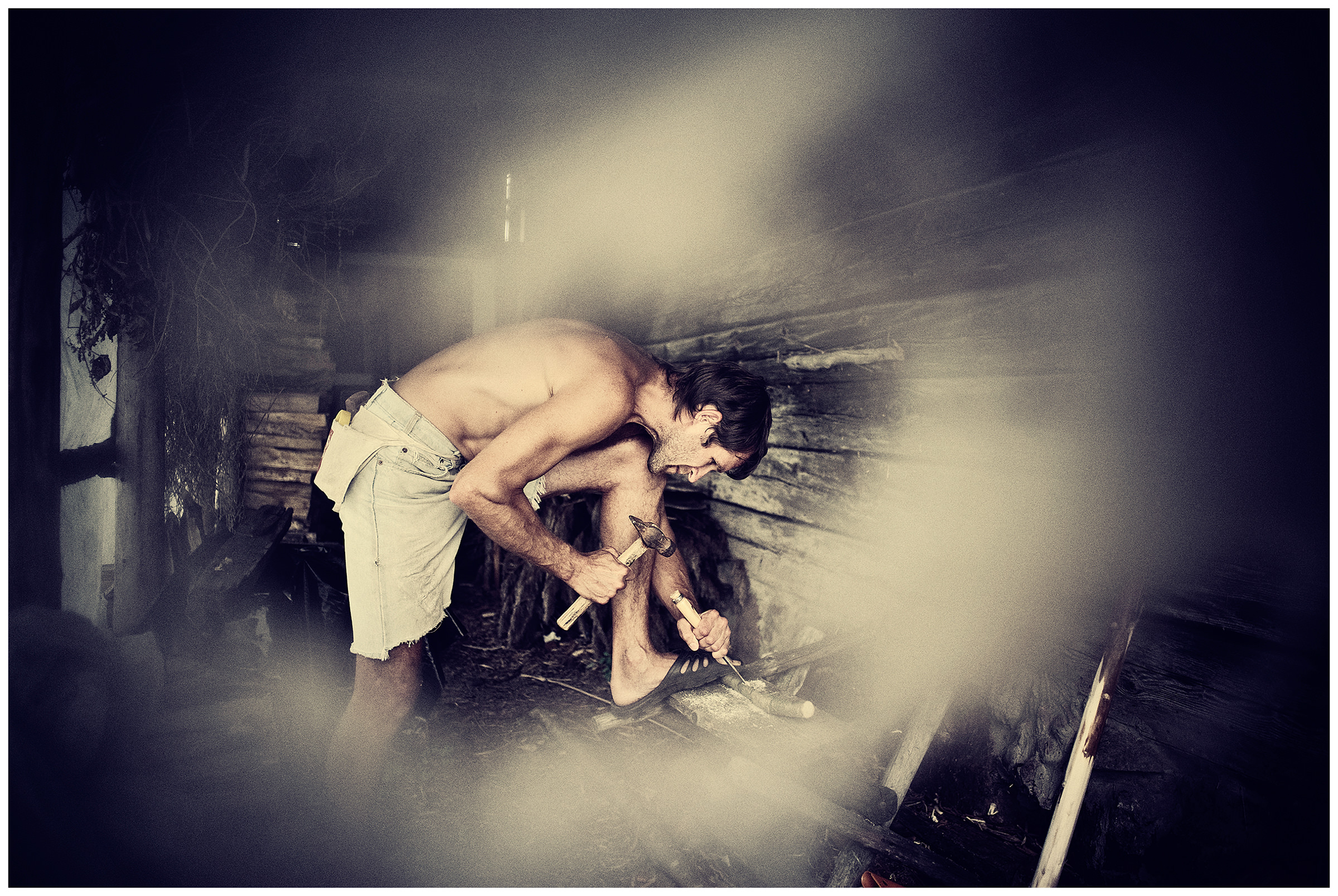 Belarus, village of Chereshlya. A man carves in a barn.