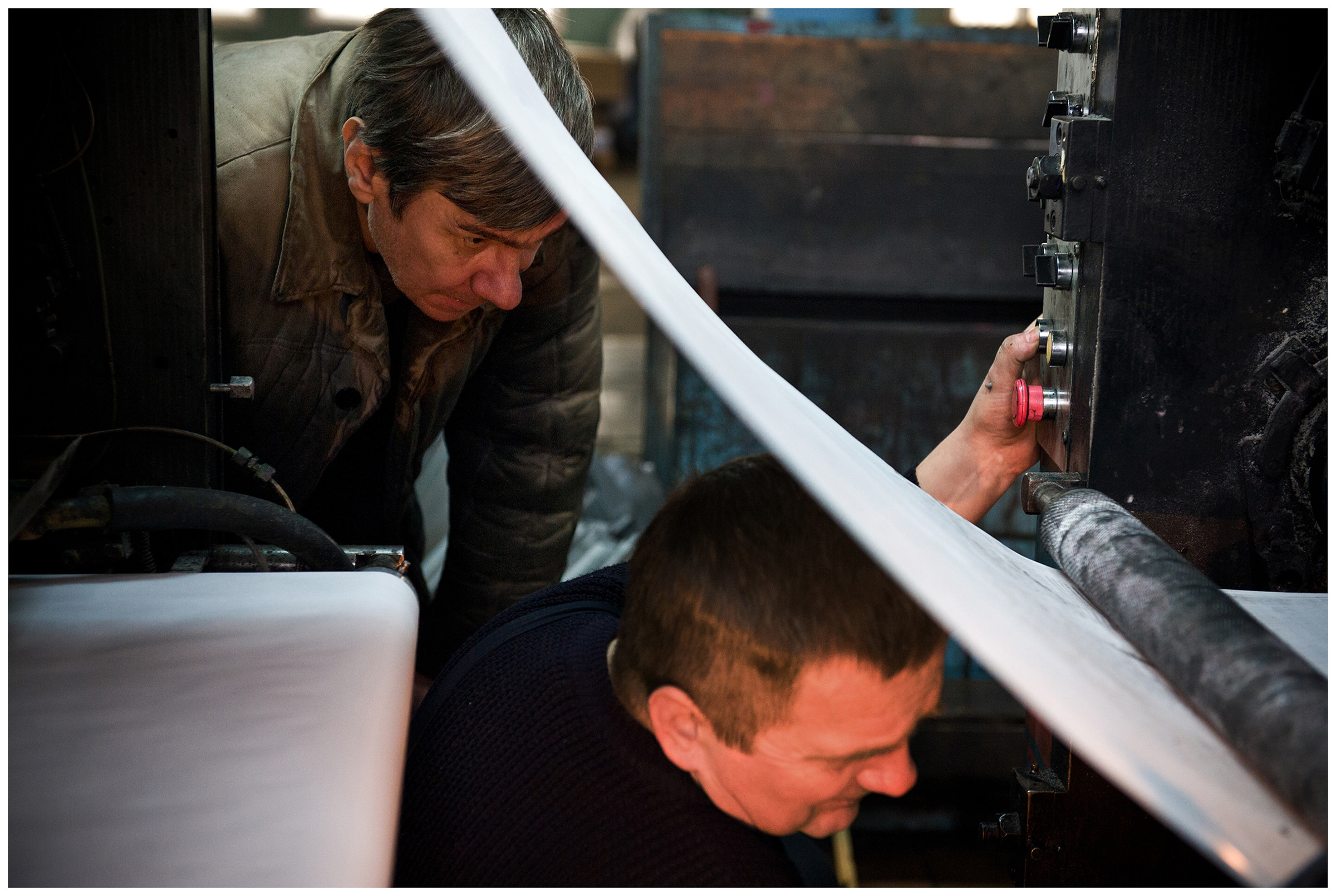 Minsk, Belarus, the publishing house "Pechatny Combinat". Two technicians repair a printing press.