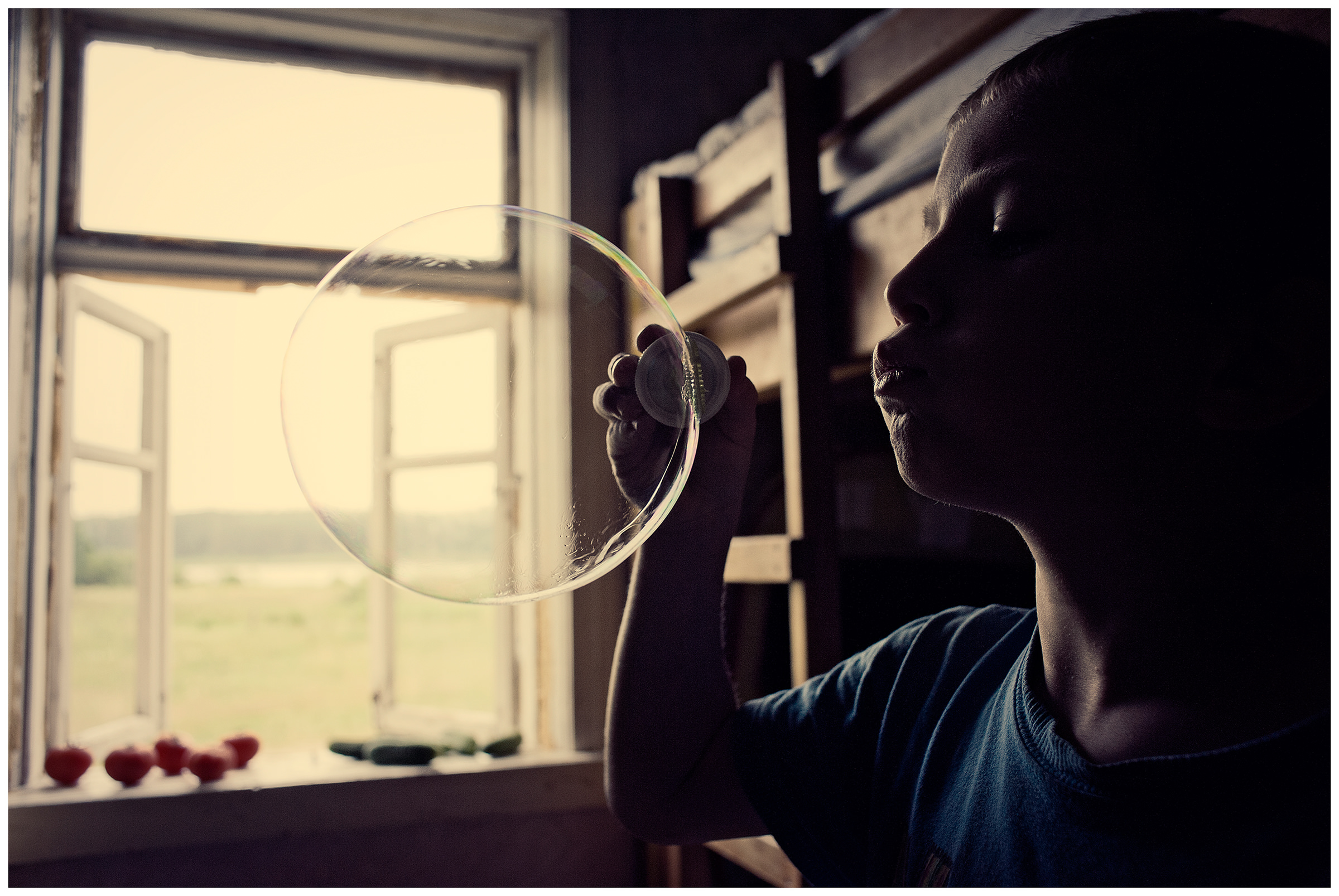 Belarus, village of Chereshlya. A boy makes soap bubbles.