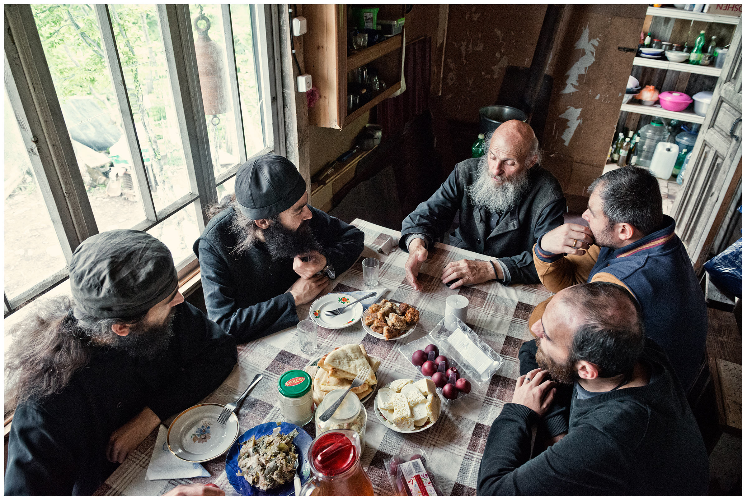 Imereti, Georgia. The Georgian monk Maxime Kavtaradze eats with his friends at a table in his house on the rock.