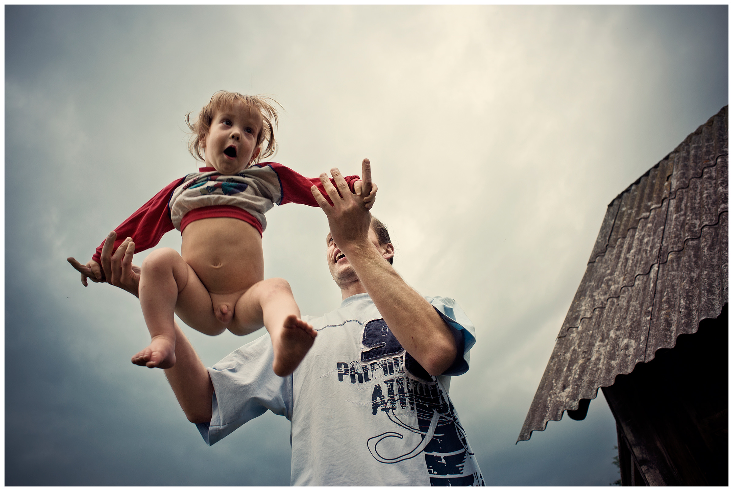 Belarus, village of Chereshlya. A man throws up his son.