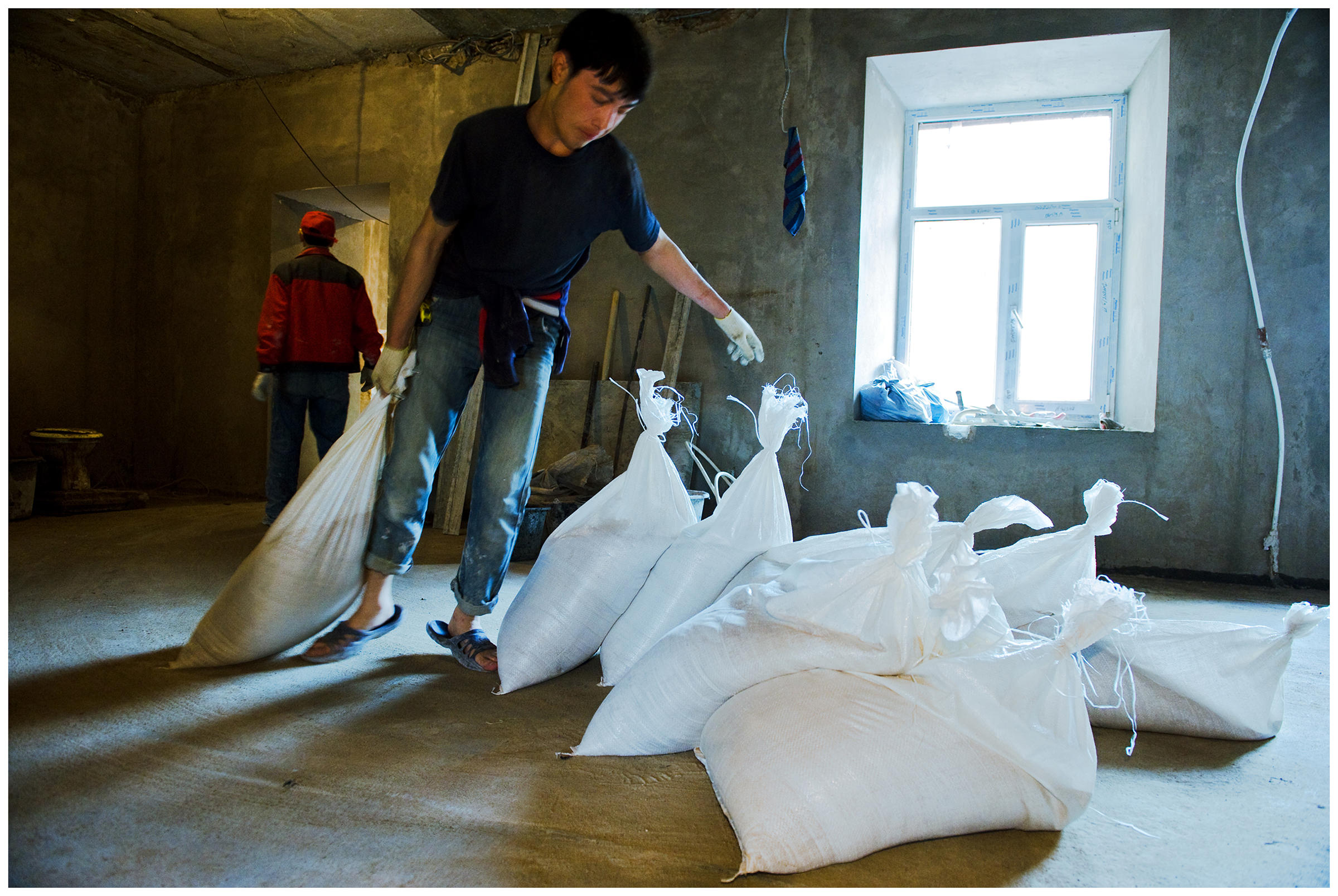 Saint Petersburg, Russia. An Uzbek guest worker drags a sack of cement to a construction site.