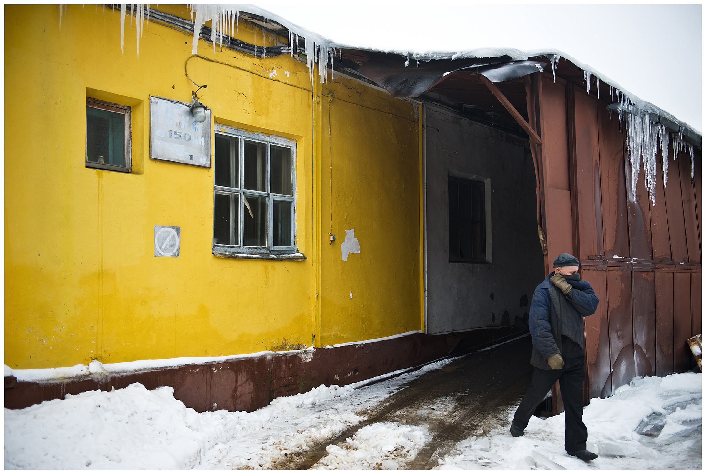 Minsk, Belarus, the publishing house "Pechatny Combinat". A worker leaves the paper warehouse. Since the air in the camp must always be very dry and cold and humid outside, the young man has to protect his respiratory tract.