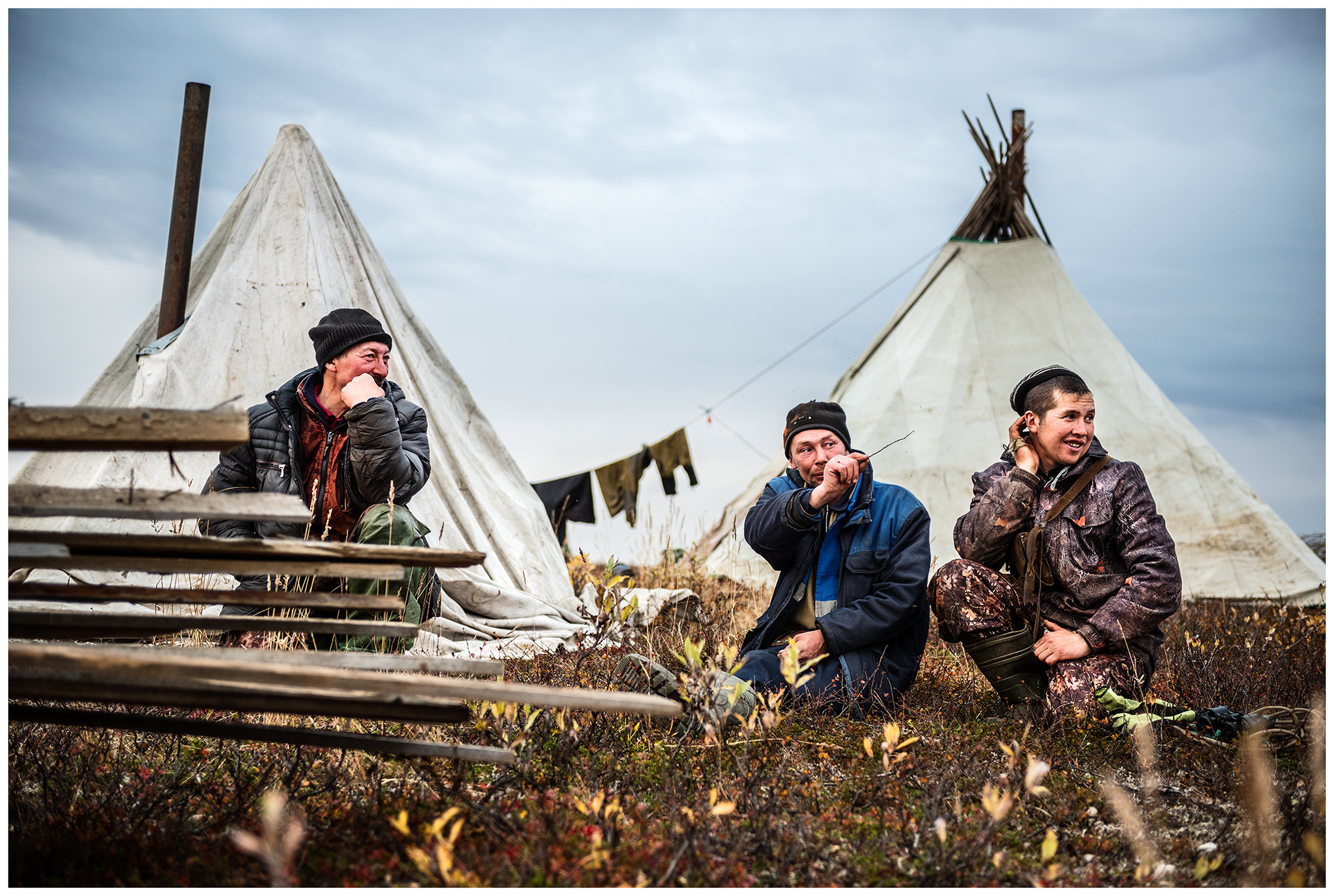 Nenets Autonomous Okrug, Komi Republic, Russia. Reindeer herders sit in front of their tents.