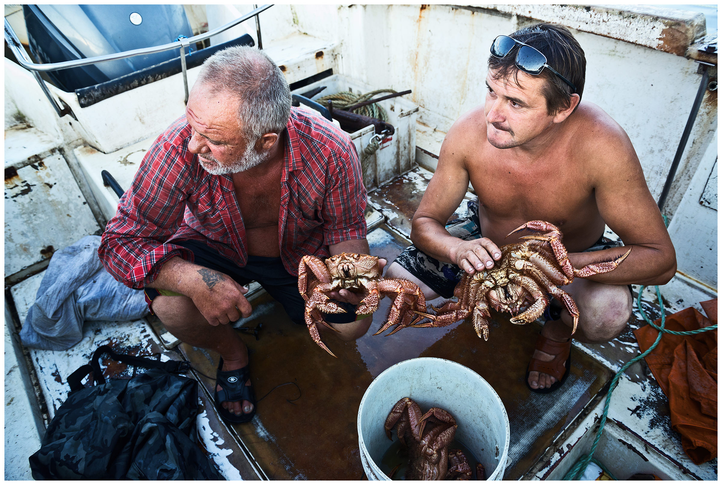 Sea of Japan, Russia. Two poachers have moored their cutter in the harbour of Posyet and are sorting the caught crabs on board.