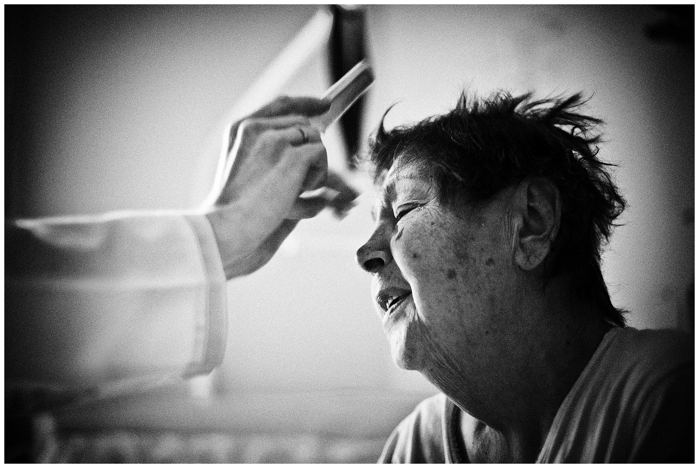 Minsk Hospice, Minsk, Belarus. A nurse is combing the hair of a patient.