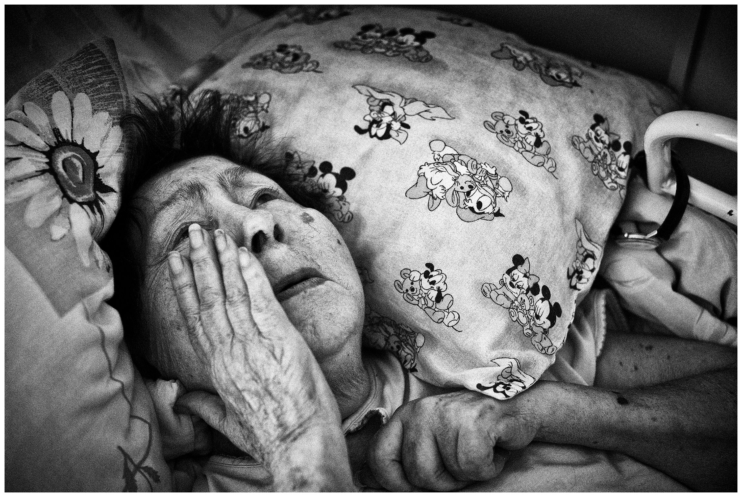 Minsk Hospice, Minsk, Belarus. A patient cries in her bed.