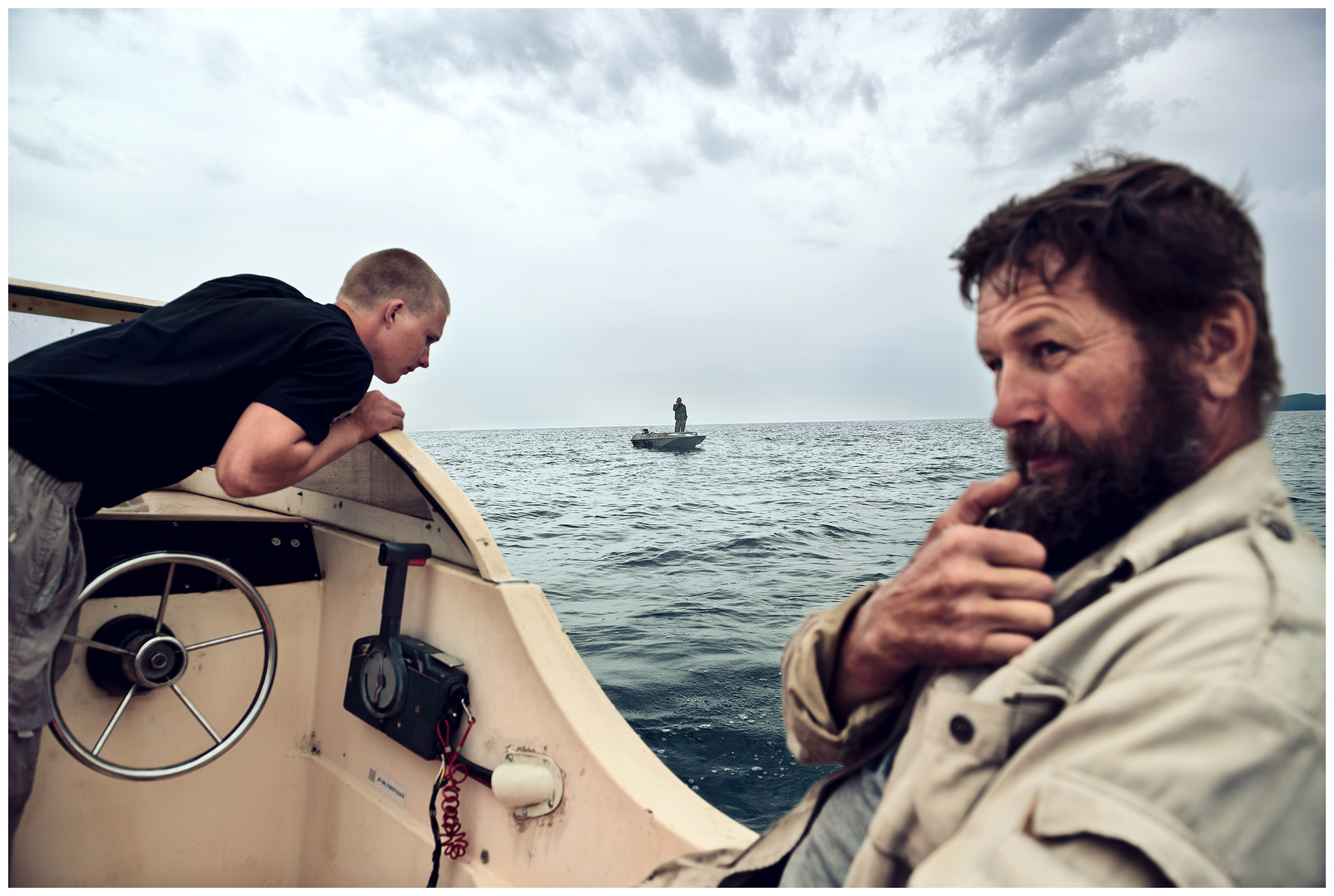 Peter the Great Bay, Sea of Japan, Russia. A man in a boat meets the poachers in the sea, for whom he fills breathing air bottles.