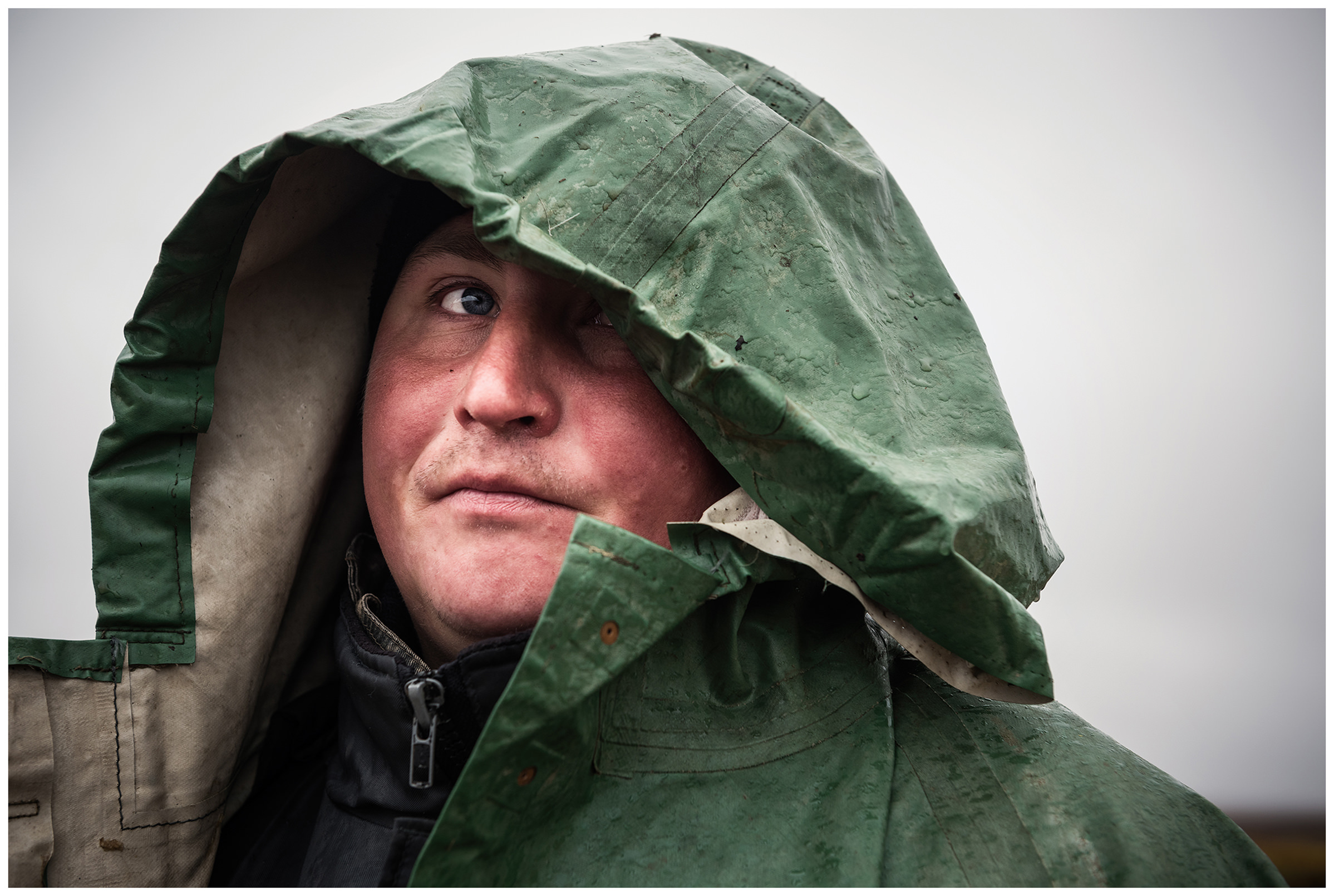 Nenets Autonomous Okrug, Komi Republic, Russia. A reindeer herder standing in a raincoat with a hood.