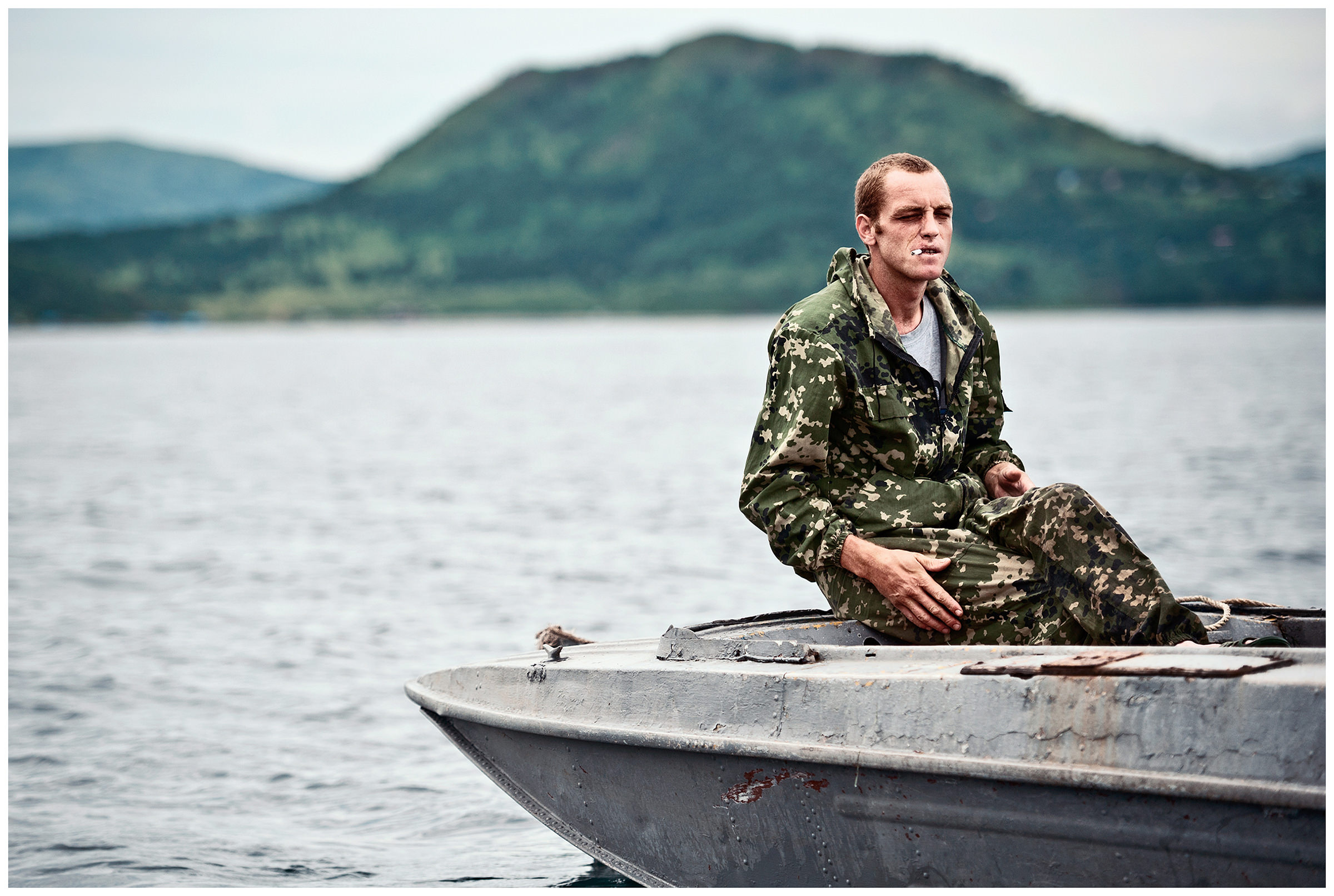 Peter the Great Bay, Sea of Japan, Russia. A poacher waits a boat for his colleague who catches scallops under the water.