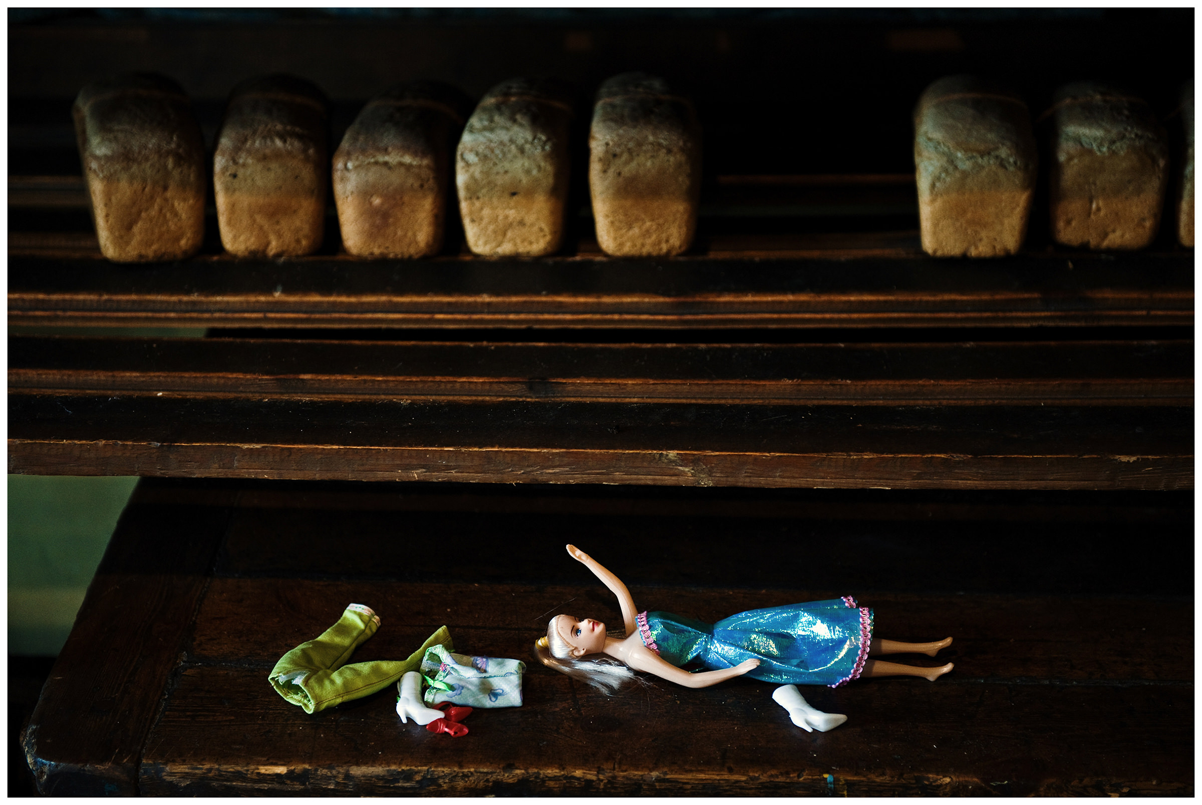 Shoyna village, Russia. A doll lies in a bakery next to the breads.