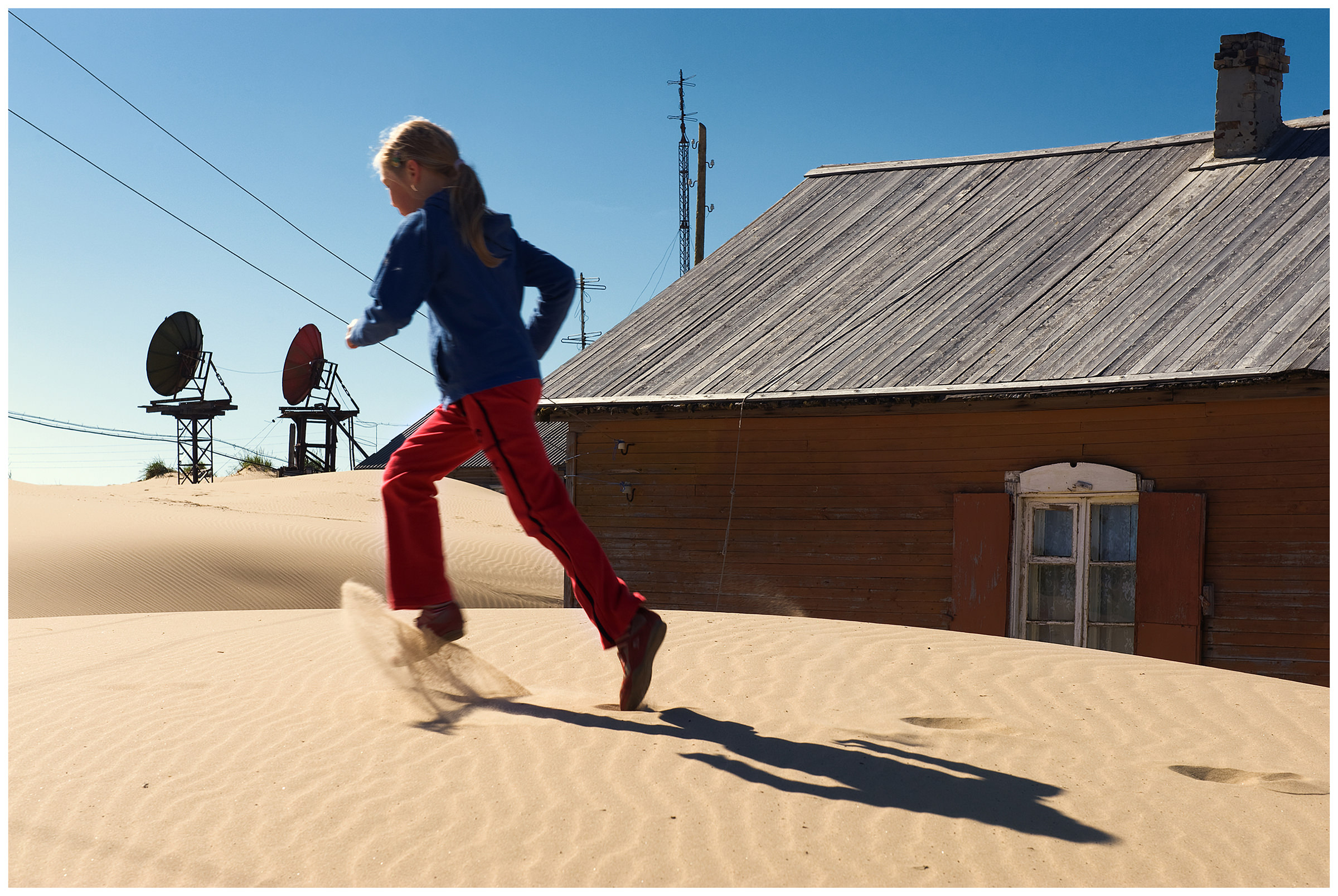 Shoyna village, Russia. A girl walks through the sand.