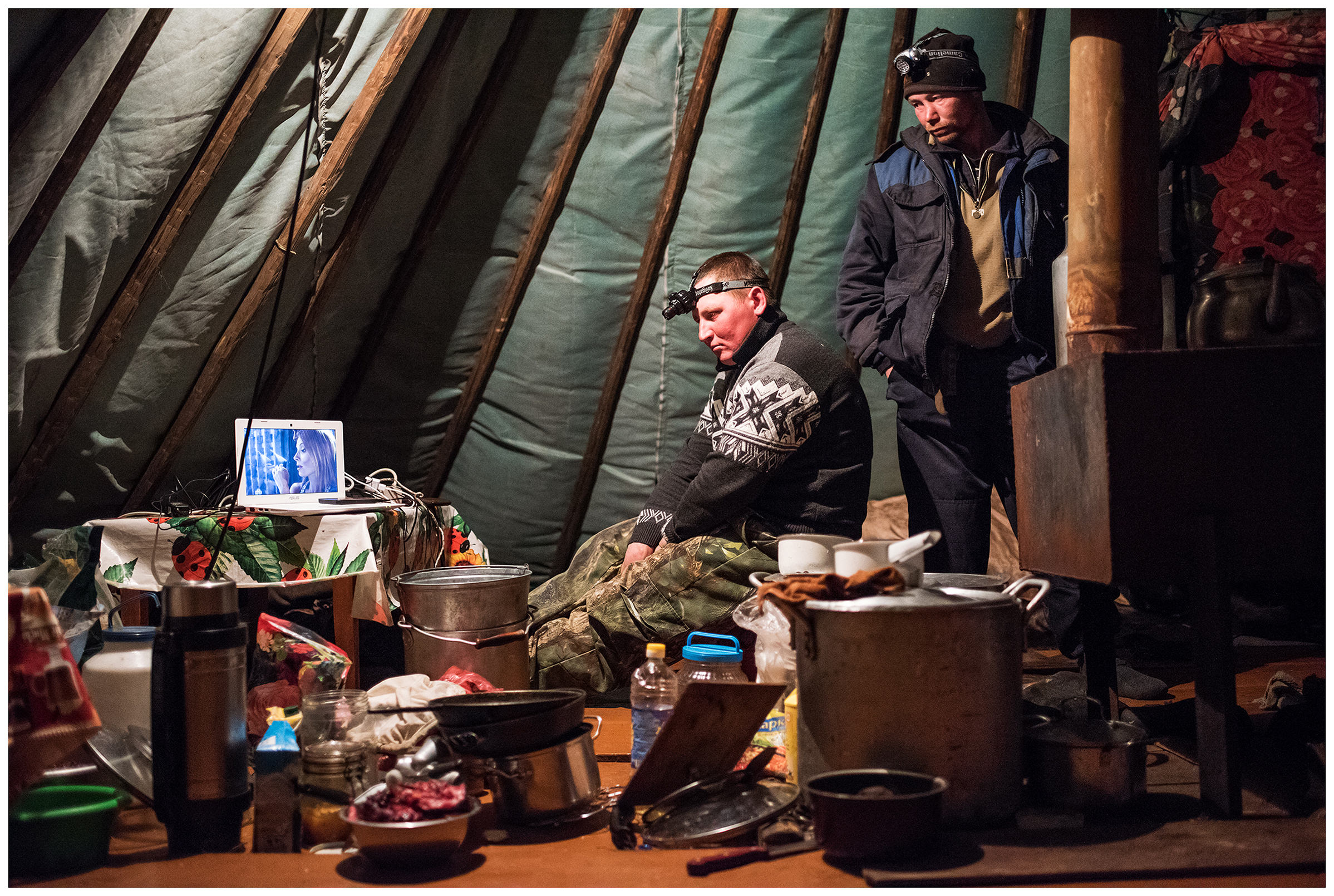 Nenets Autonomous Okrug, Komi Republic, Russia. Reindeer breeders watching a film on a laptop.