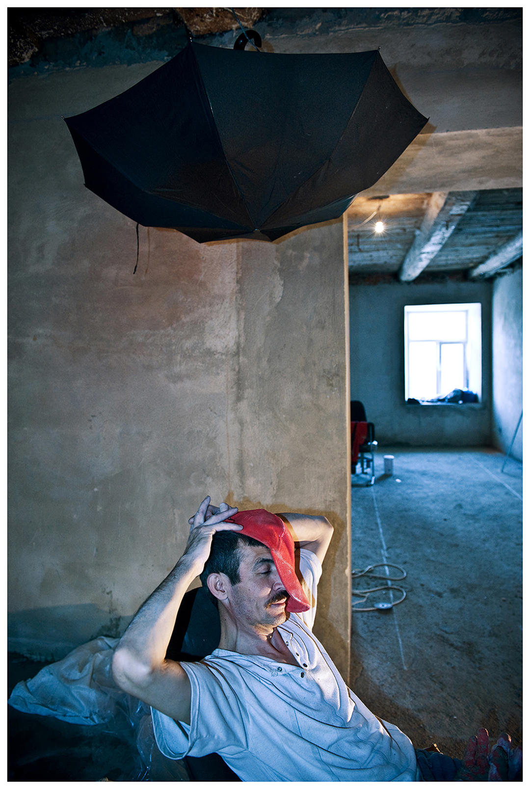 Saint Petersburg, Russia. An Uzbek guest worker sits under an umbrella, taking a break at a construction site.