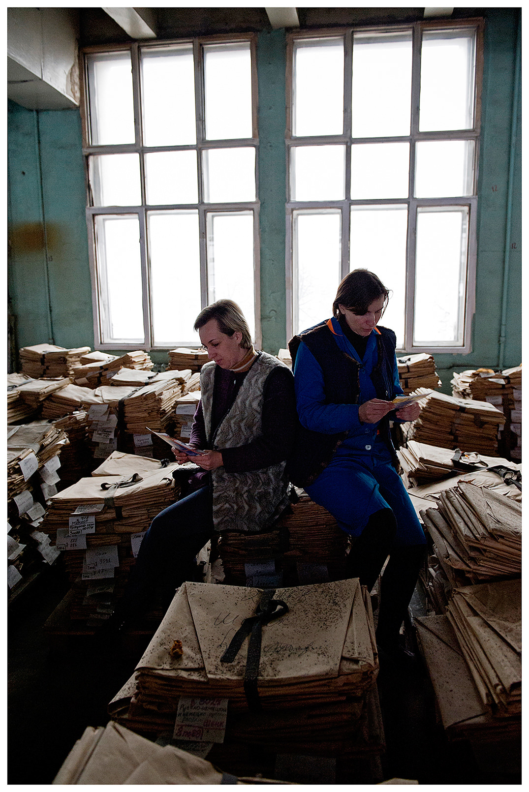 Minsk, Belarus, the publishing house "Pechatny Combinat". Two workers sit on the packed old printing forms and compare technical tasks.