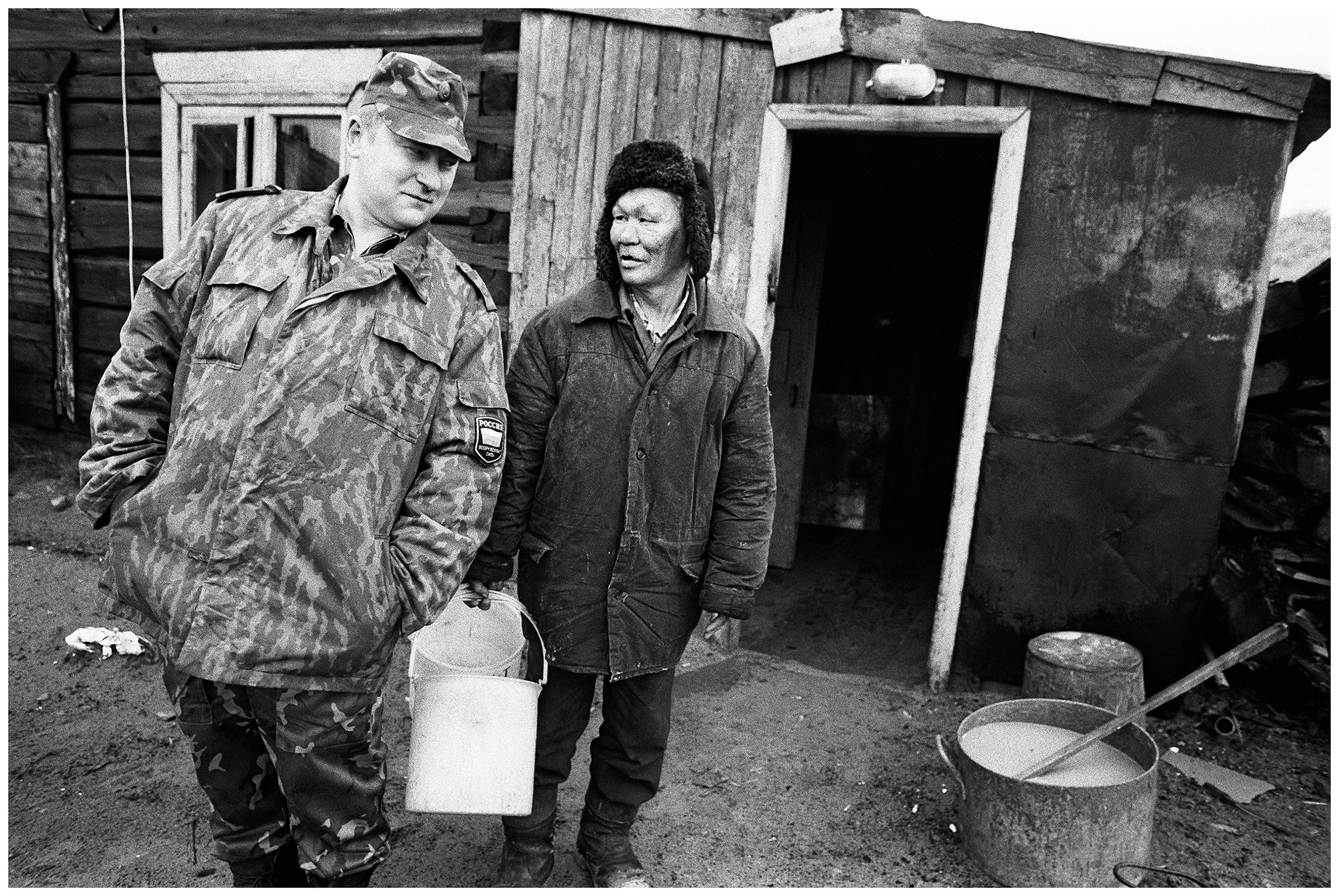A soldier and a stoker stand in front of a house