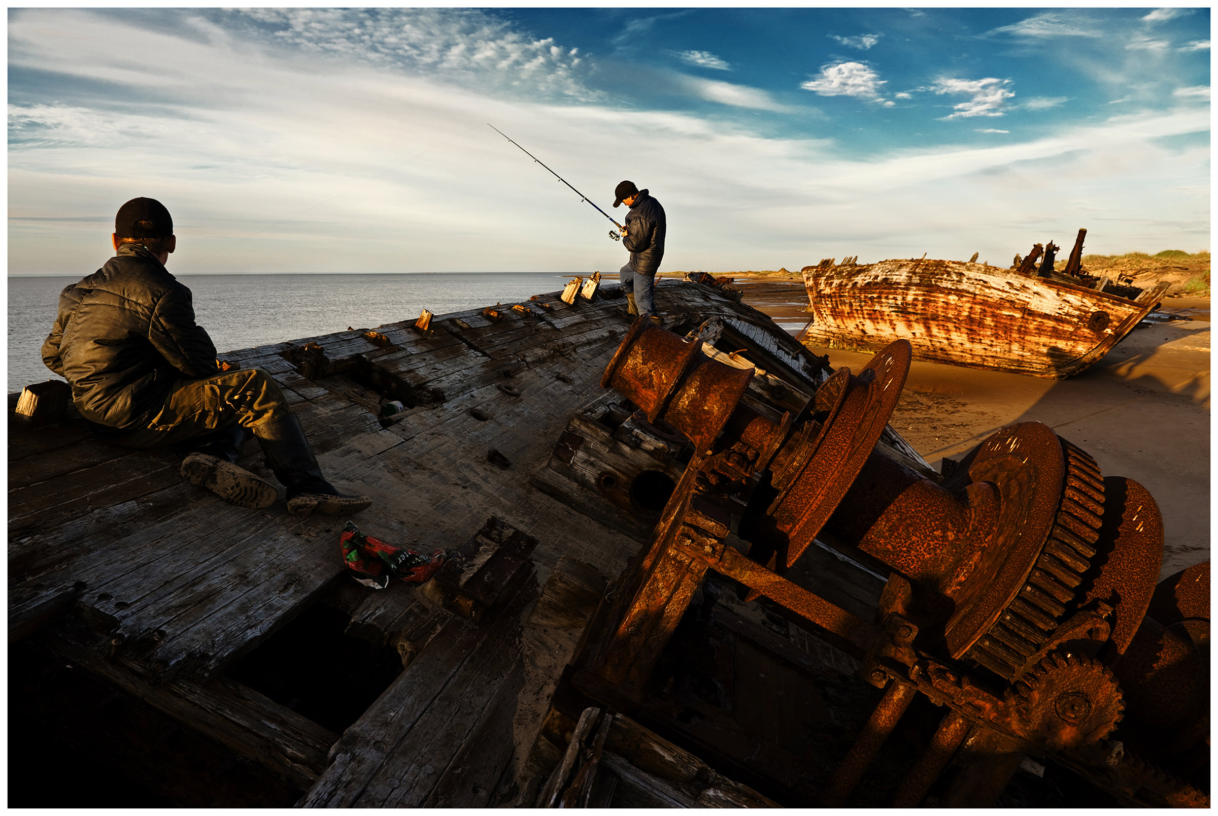 Shoyna village, Russia. Two boys fishing from the ship wraks.