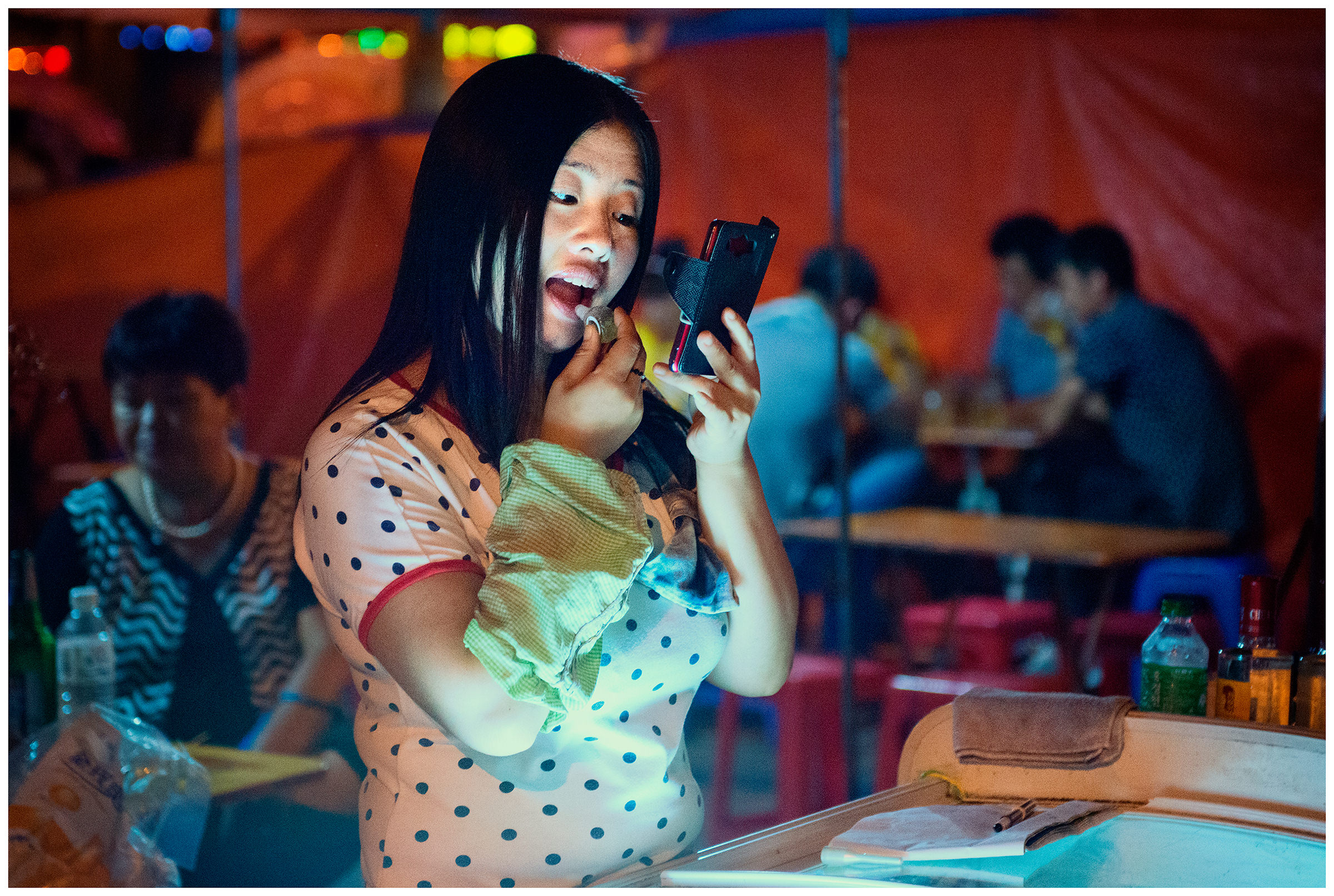 A Chinese seller of Russian seafood makes herself up in a Hunchun market.