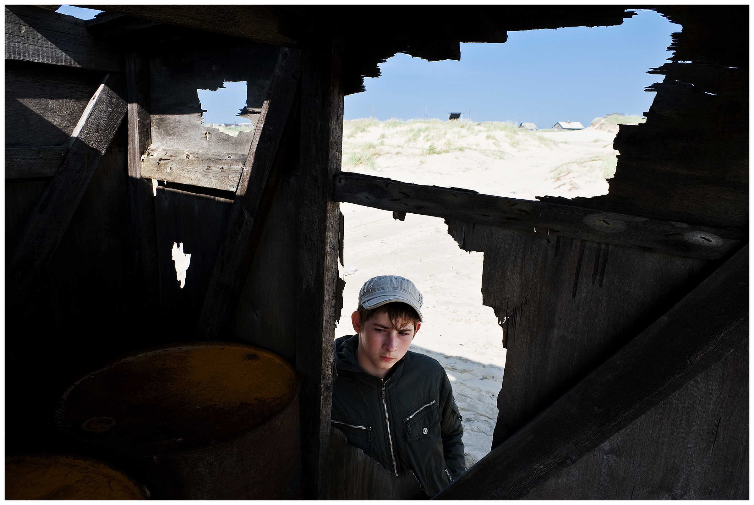 Shoyna village, Russia. A boy stands in front of a destroyed house.