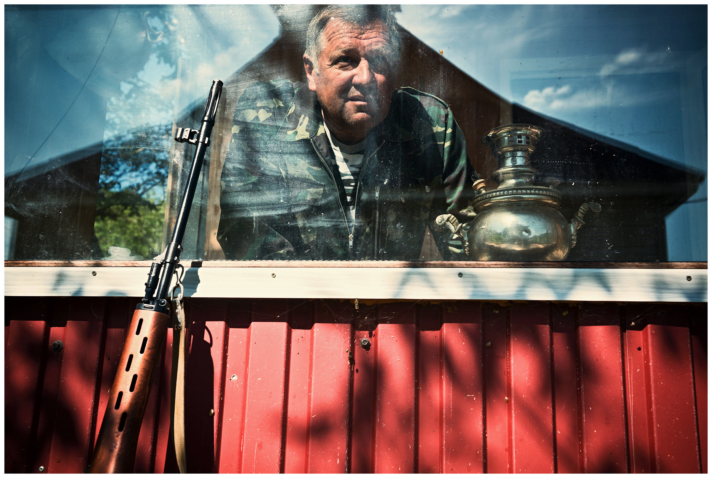 A border guard observes the sea. In front of his house there is a gun.