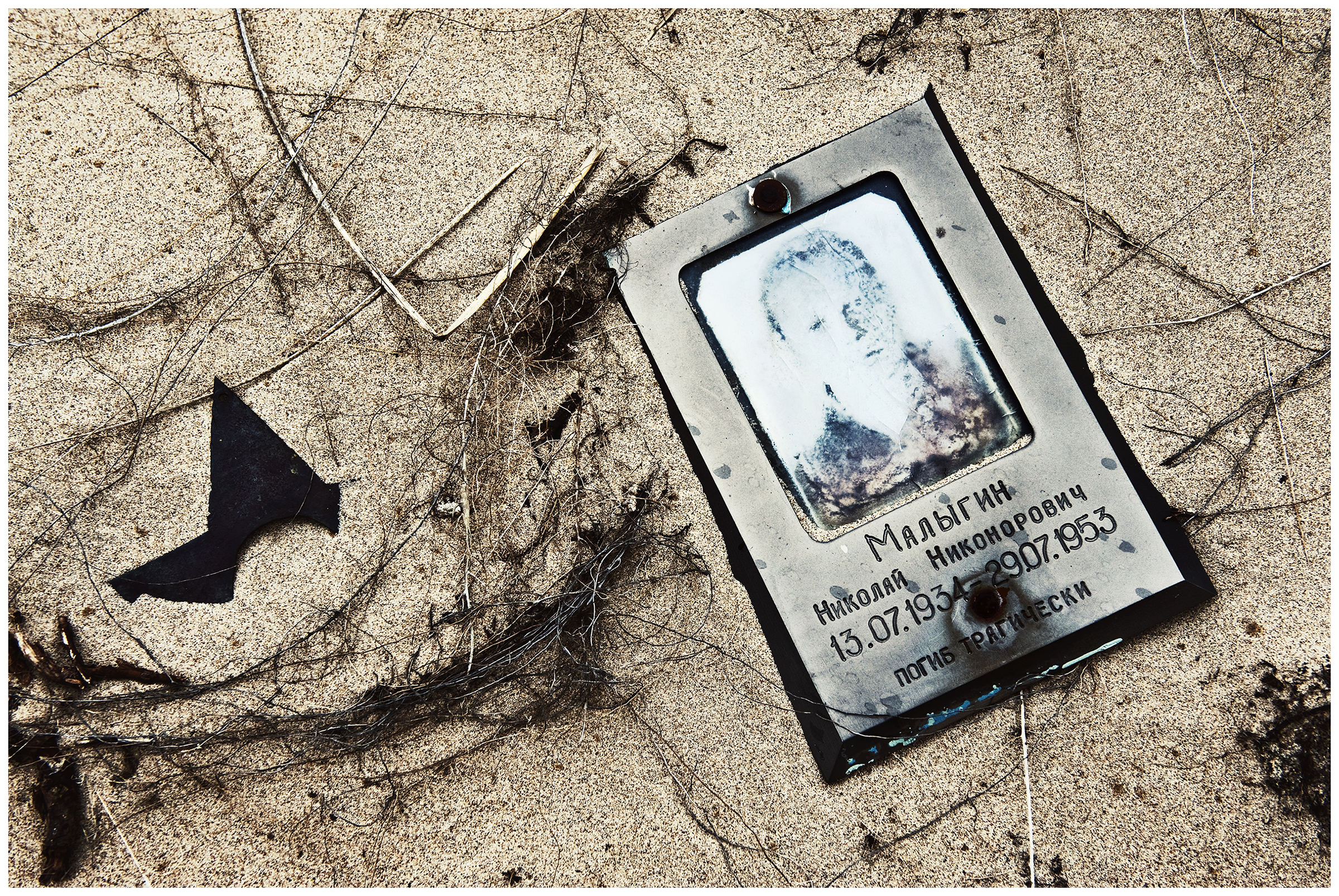 Shoyna village, Russia. Portrait of a deceased man lying in the sand of a cemetery.