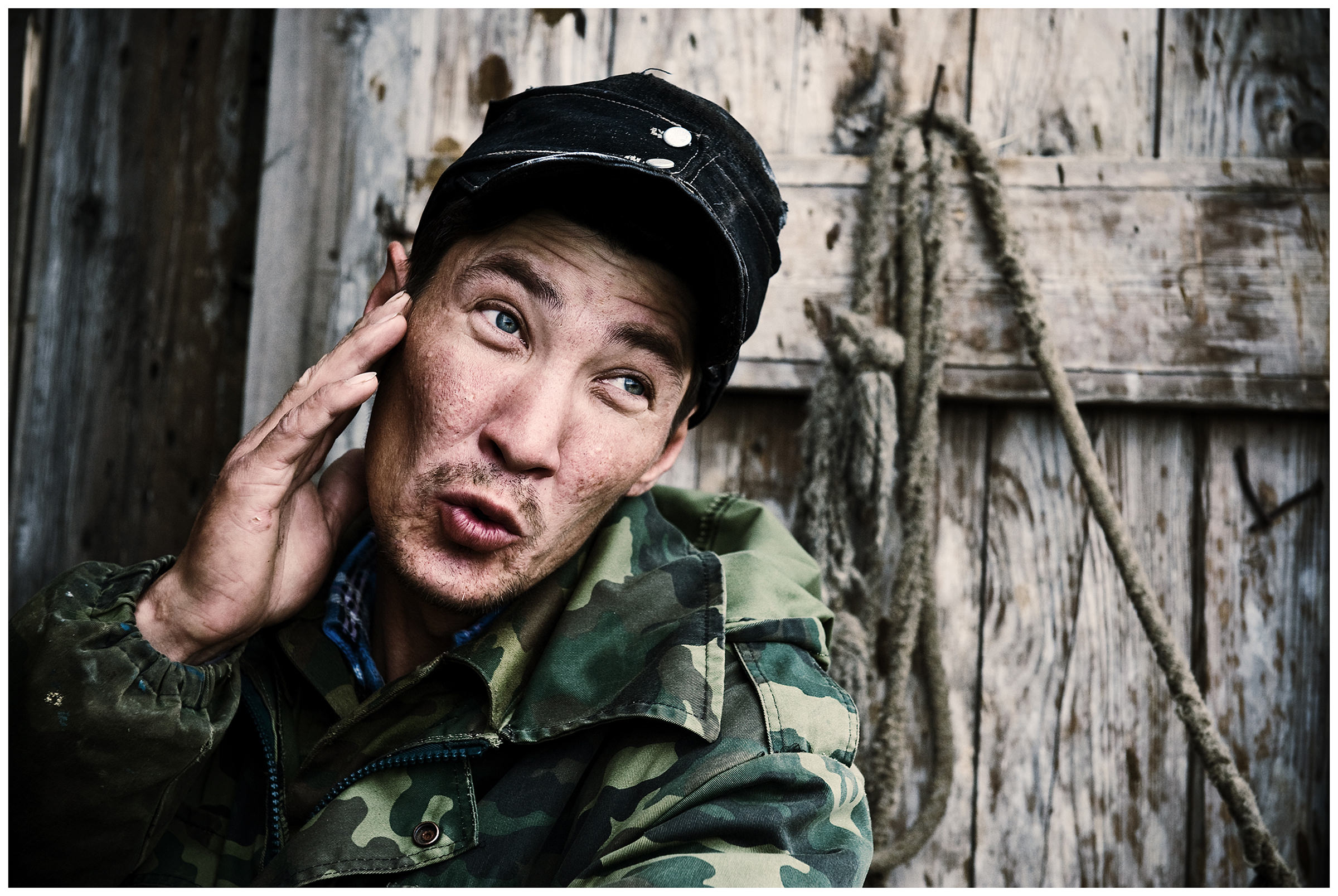 Shoyna village, Russia. A man sits in front of a wooden house.