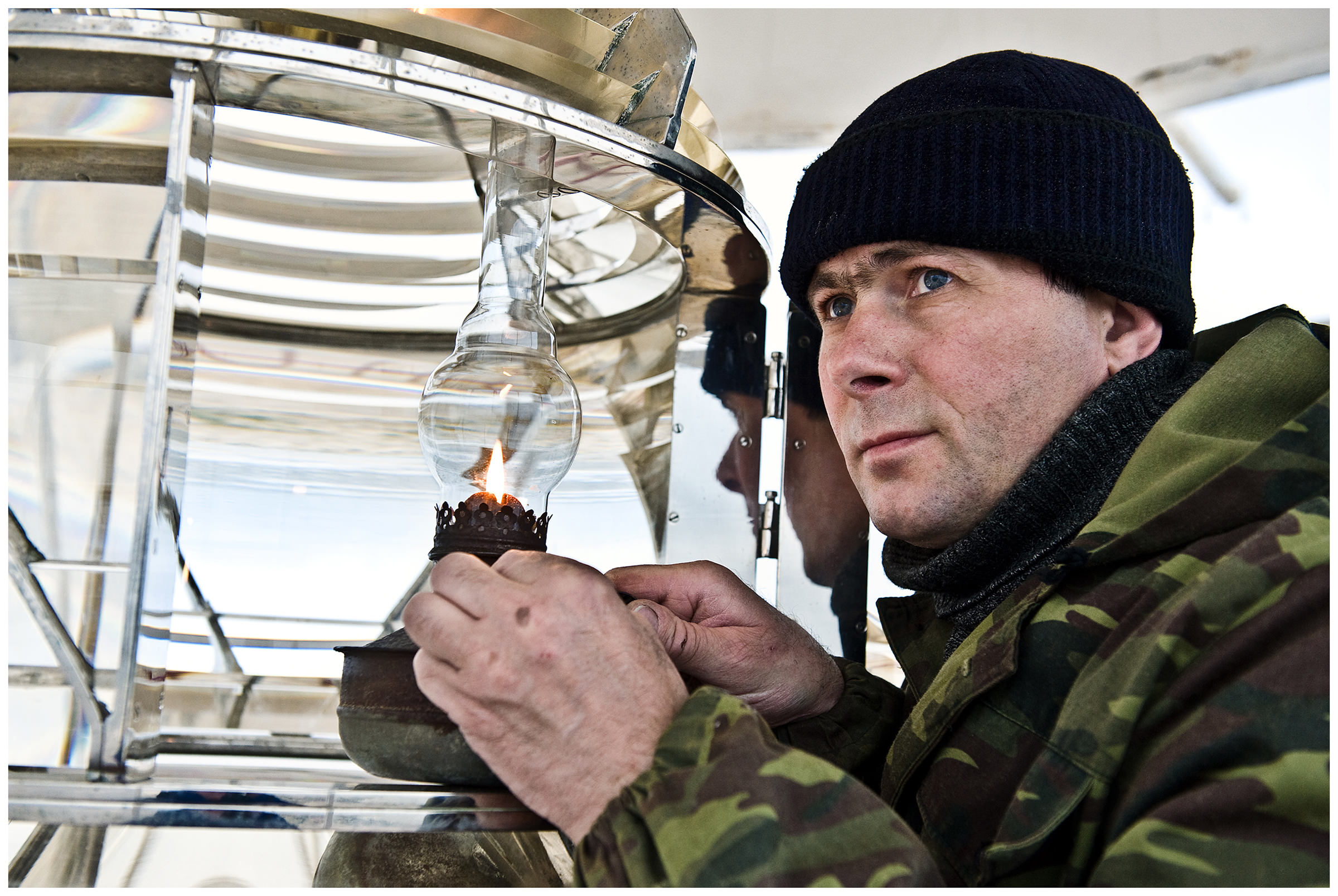 Shoyna village, Russia. A lighthouse keeper lights a kerosene lamp in his lighthouse.
