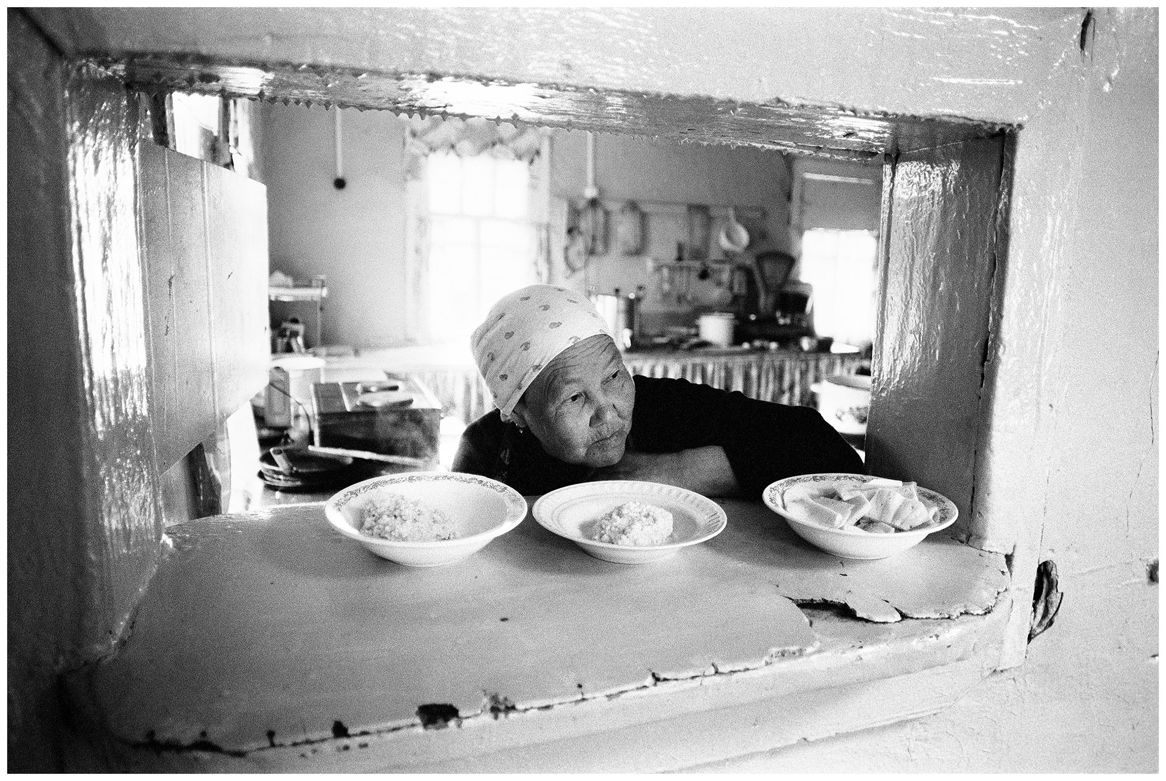 Shoyna village, Russia. A cook in the boarding school serves the food in the plates.