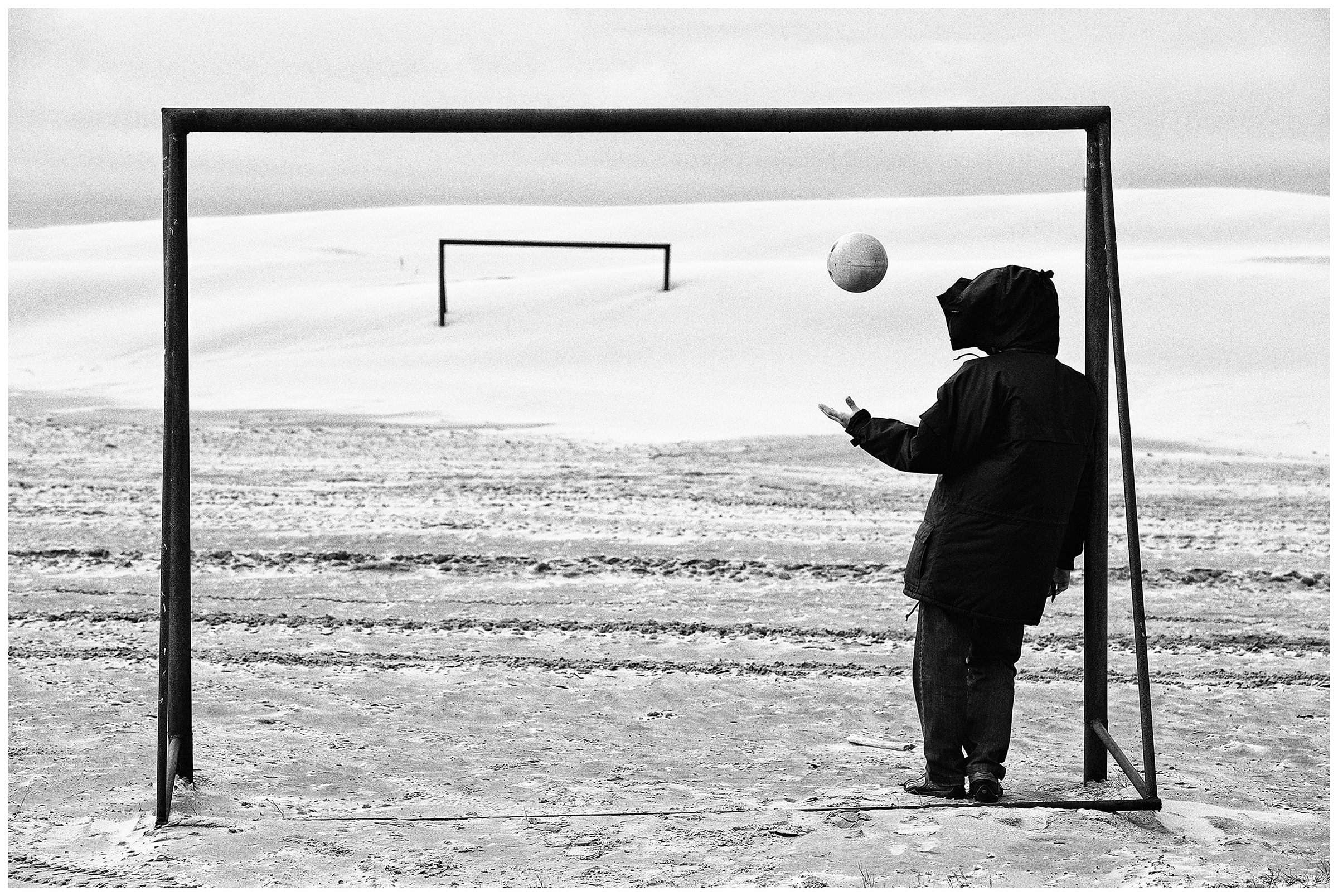Shoyna village, Russia. A man plays on a football field with a net swimmer.