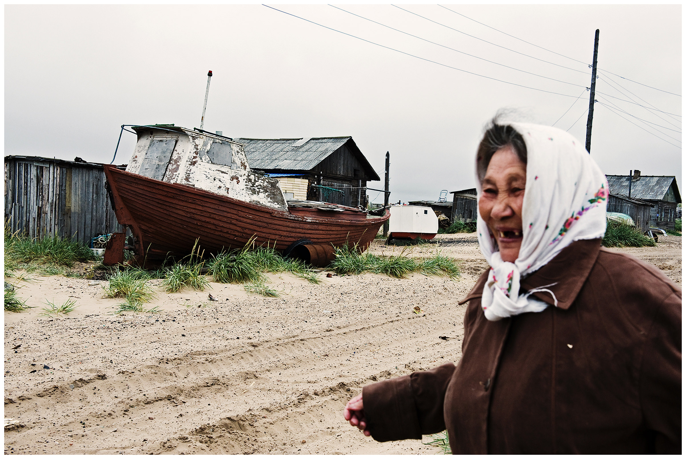 Shoyna village, Russia. An old woman in a headscarf walks through the village.